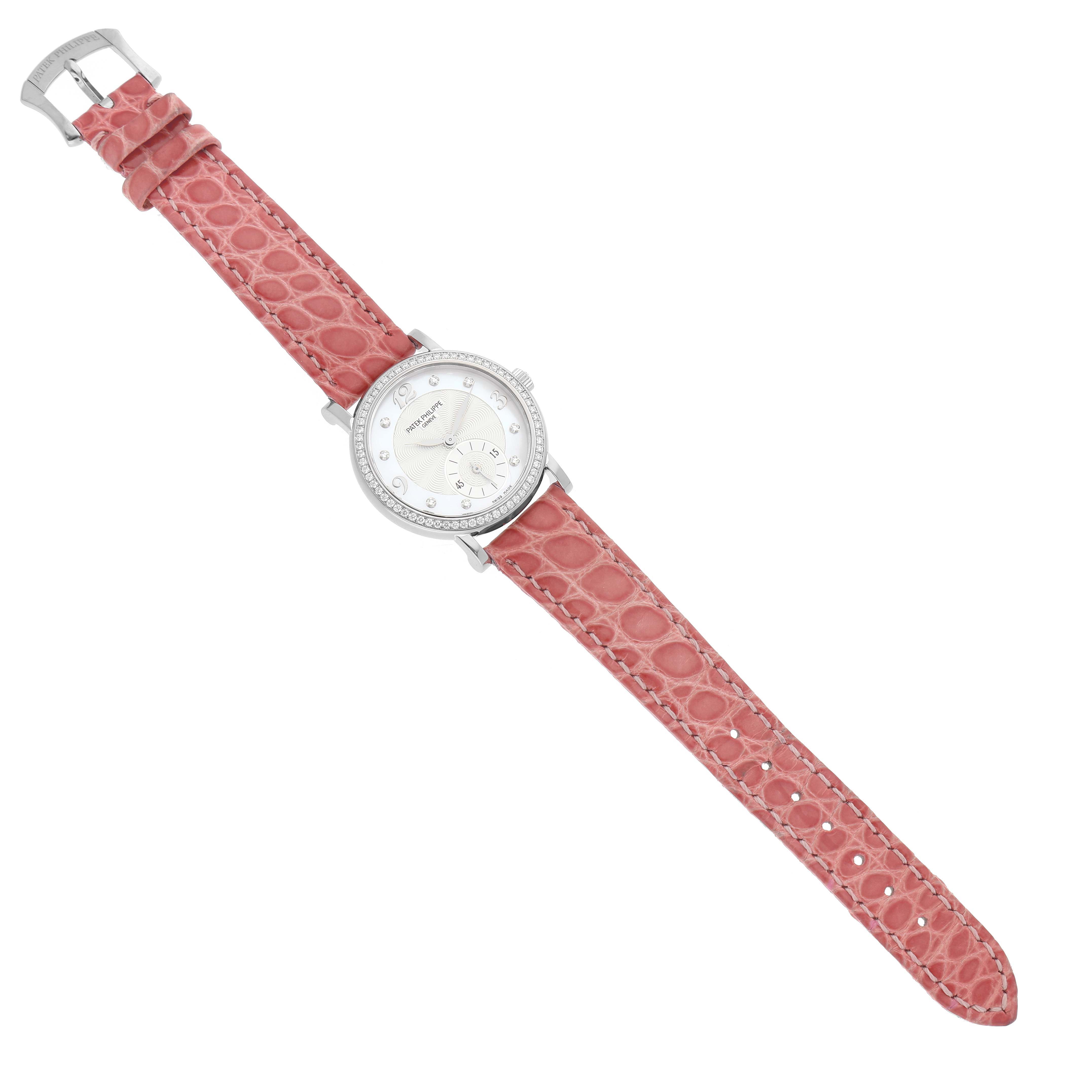 The Patek Philippe Calatrava 4959G Women's White Gold Silver Dial watch is shown from a top-down angle, featuring a pink textured strap and a round, jeweled bezel.