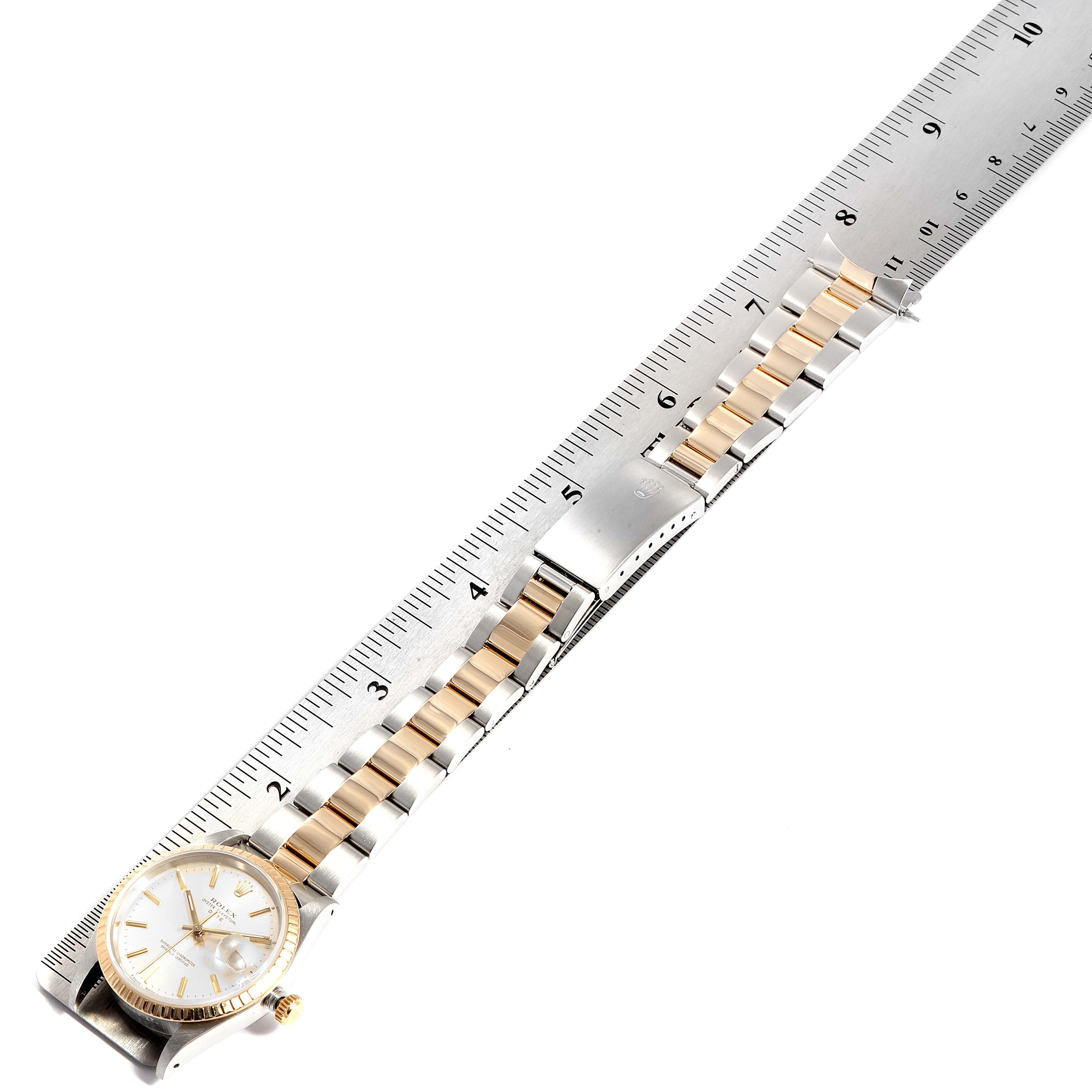 The image shows a side view of the Rolex Date 15223 Men's Steel and Gold (two tone) Silver Dial 15223 Men's Steel and Gold (two tone) Silver Dial model watch with its two-tone metal bracelet and a ruler for scale.