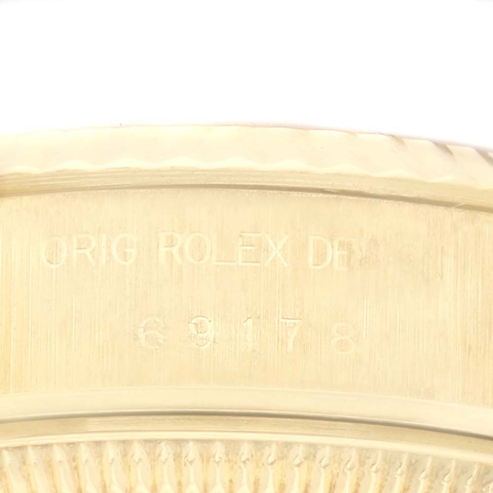 The image shows a close-up of the engraved text and serial number on the case of a Rolex President 69178 Women
s Yellow Gold Champagne Dial 69178 Women
s Yellow Gold Champagne Dial model.