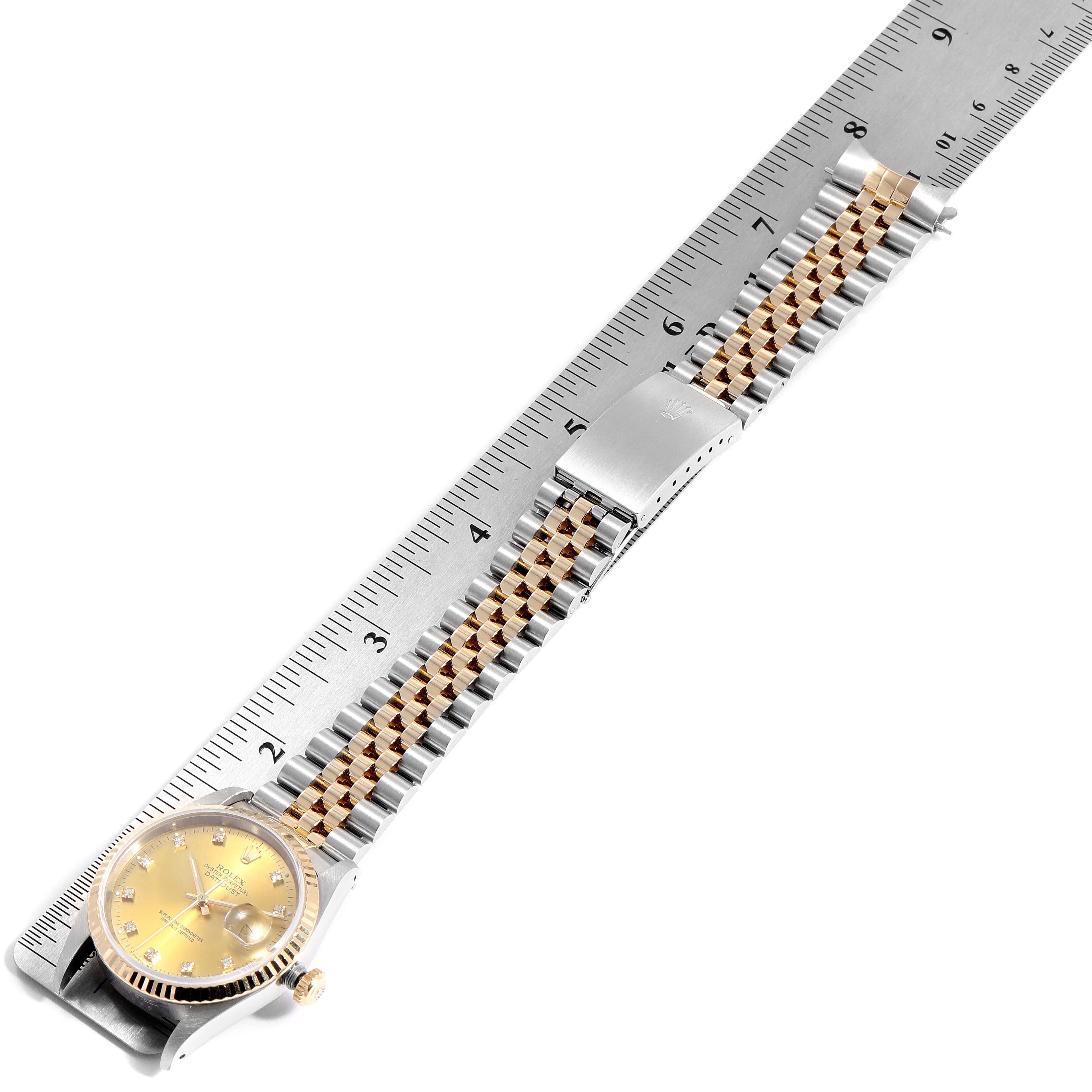 The Rolex Datejust 16233 Men
s Steel and Gold (two tone) Champagne Dial 16233 Men
s Steel and Gold (two tone) Champagne Dial watch is shown from an oblique top-down angle, highlighting its dial, crown, and bracelet alongside a ruler.