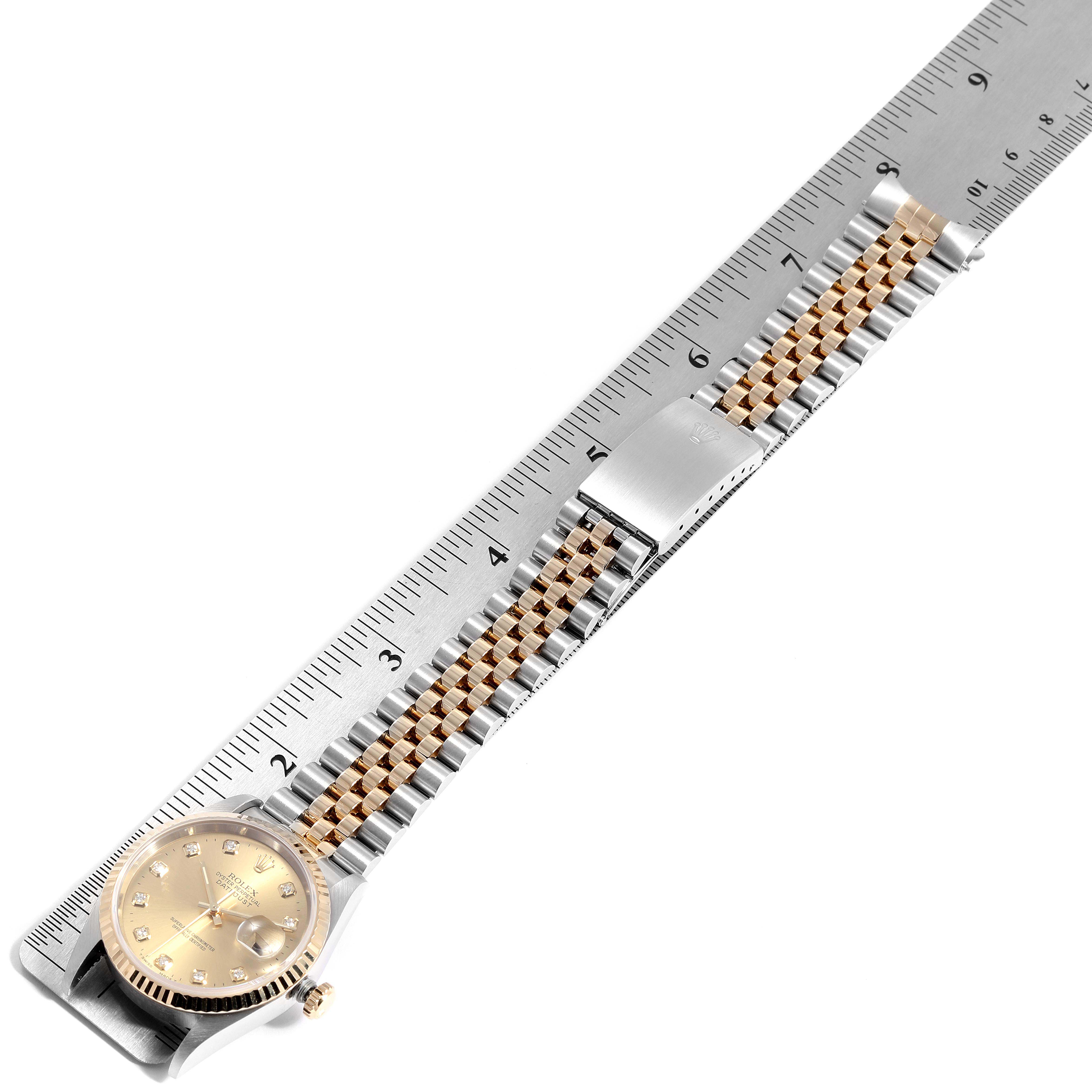 The image shows an overhead view of a Rolex Datejust 16233 Men
s Steel and Gold (two tone) Champagne Dial 16233 Men
s Steel and Gold (two tone) Champagne Dial watch with a two-tone bracelet and a ruler for measurement.