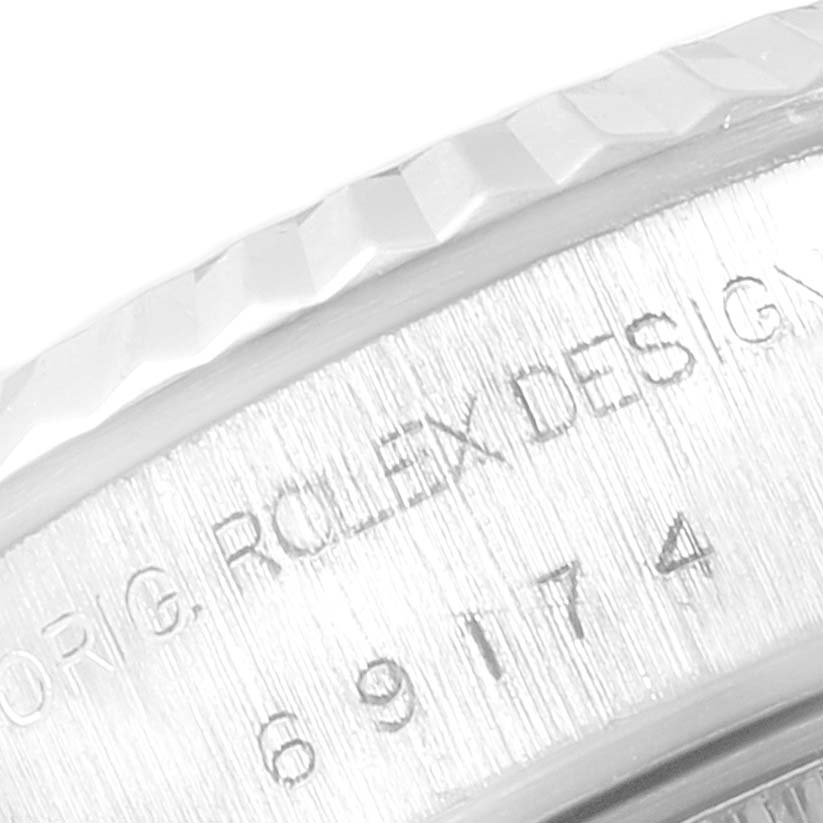 This close-up photo shows the side engraving and part of the fluted bezel of a Rolex Datejust 69174  Women
s Stainless Steel White Dial 69174  Women
s Stainless Steel White Dial watch.
