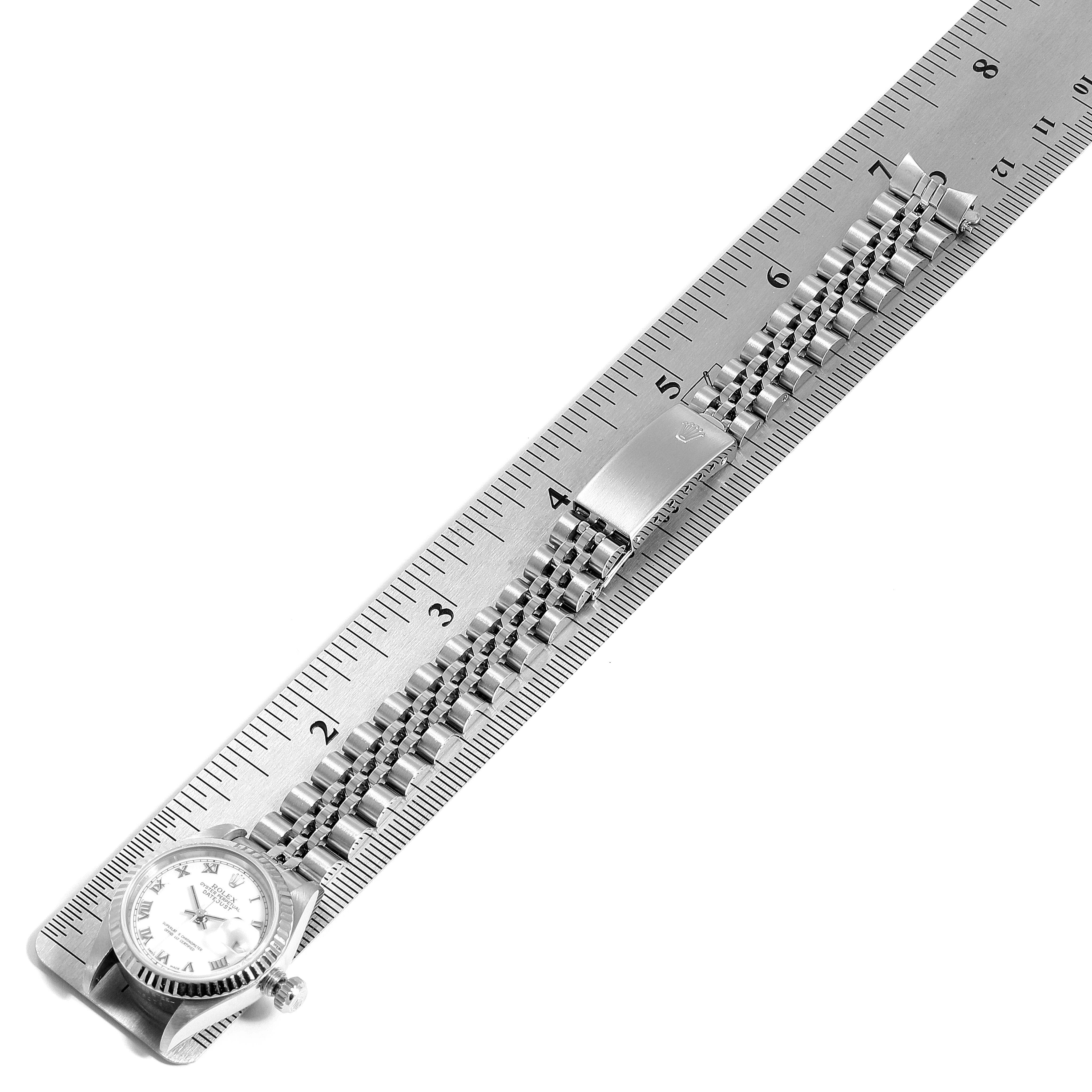 This image shows a Rolex Datejust 69174  Women
s Stainless Steel White Dial 69174  Women
s Stainless Steel White Dial watch lying next to a ruler, displaying its face, case, and bracelet from a top-down angle.
