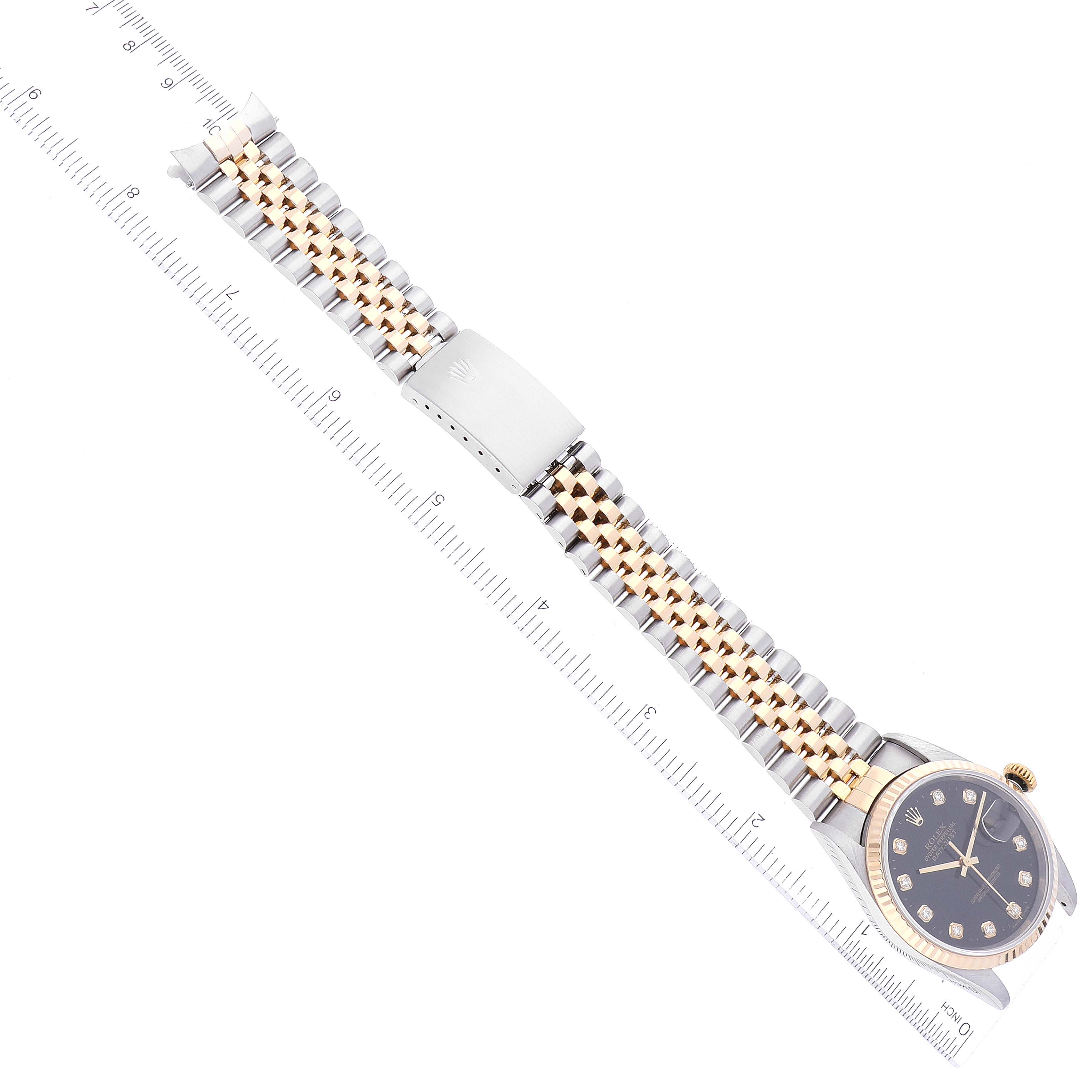 The image shows the Rolex Datejust 16233 Men's Steel and Gold (two tone) Black Dial 16233 Men's Steel and Gold (two tone) Black Dial watch lying flat, displaying the entire watchband, clasp, and face, along with a ruler for scale.