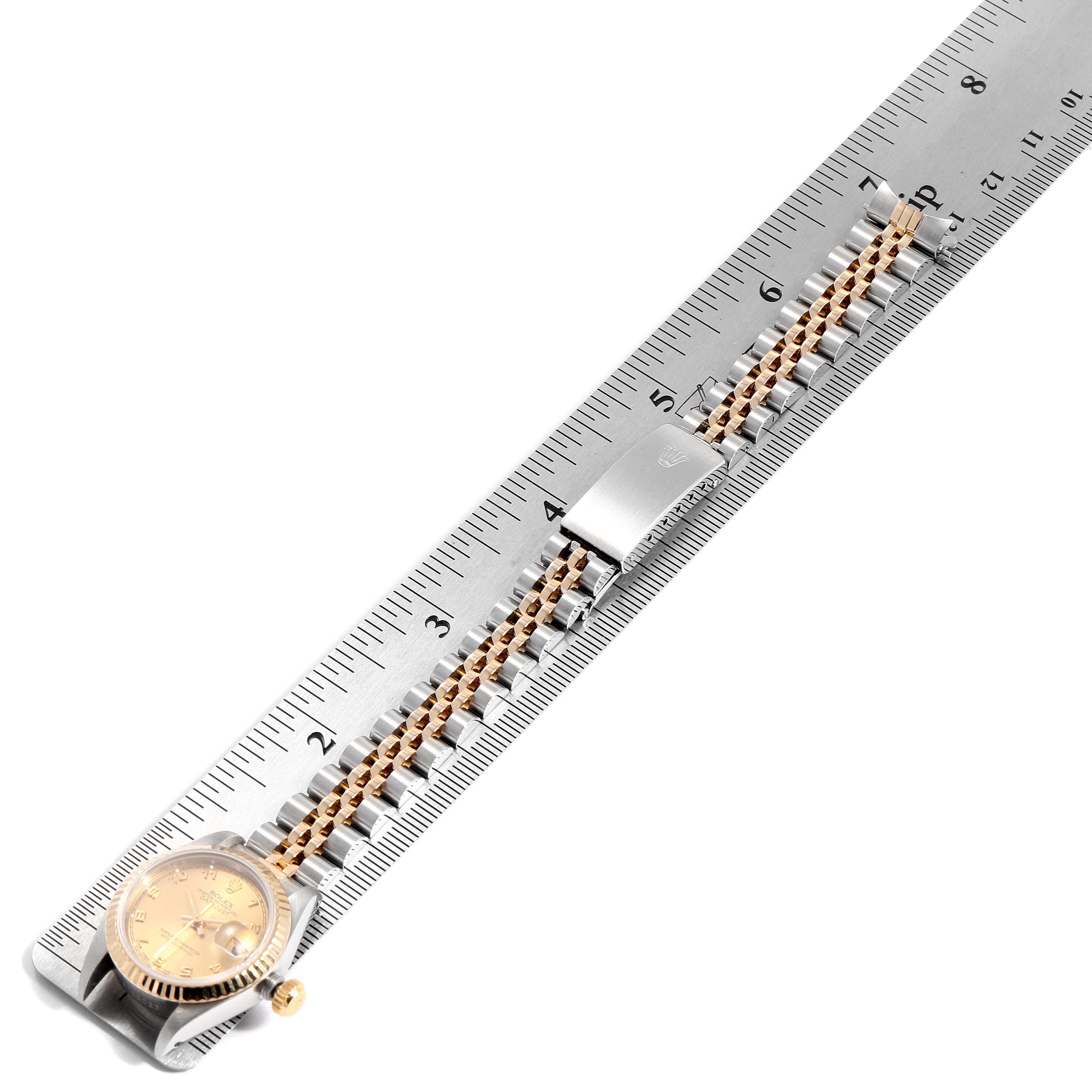The image shows a Rolex Datejust 69173 Women
s Steel and Gold (two tone) Champagne Dial 69173 Women
s Steel and Gold (two tone) Champagne Dial watch laying flat on a ruler, highlighting its bracelet and clasp.