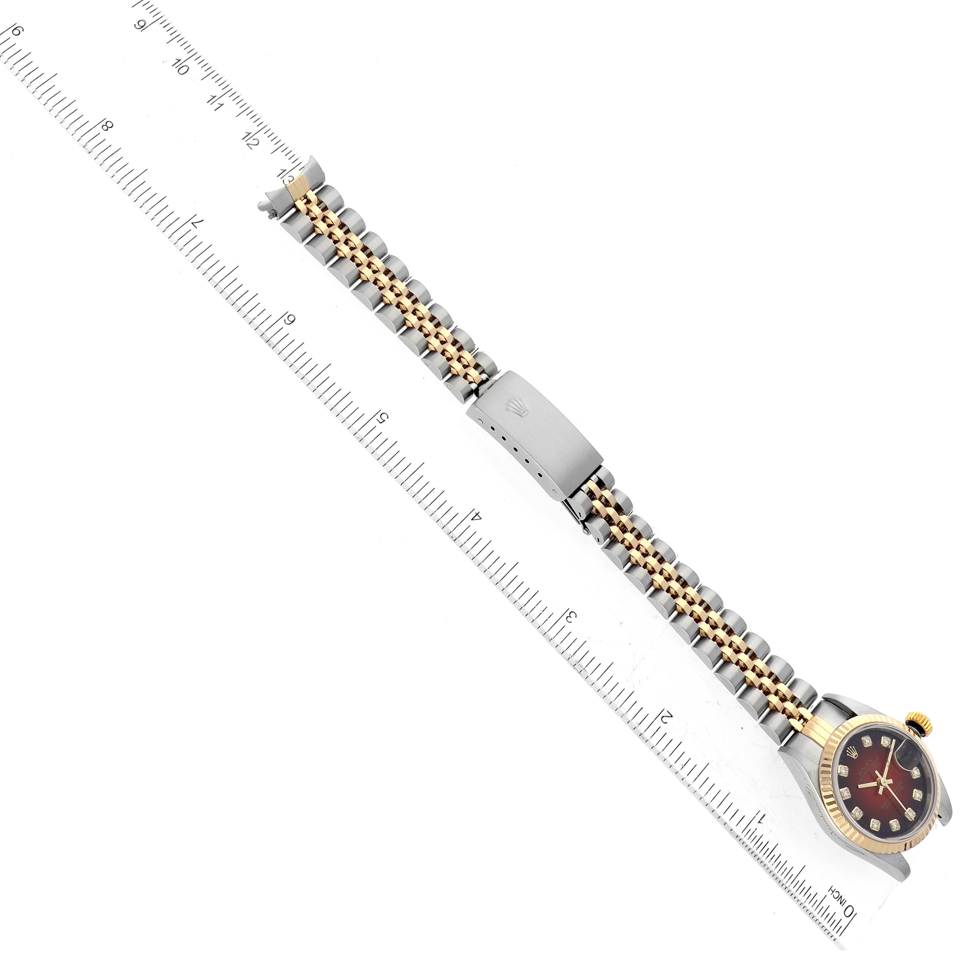 The image shows a Rolex Datejust 79173 Women's Steel and Gold (two tone) Red Dial 79173 Women's Steel and Gold (two tone) Red Dial model watch laid flat, highlighting the bracelet and clasp, alongside a ruler for scale.