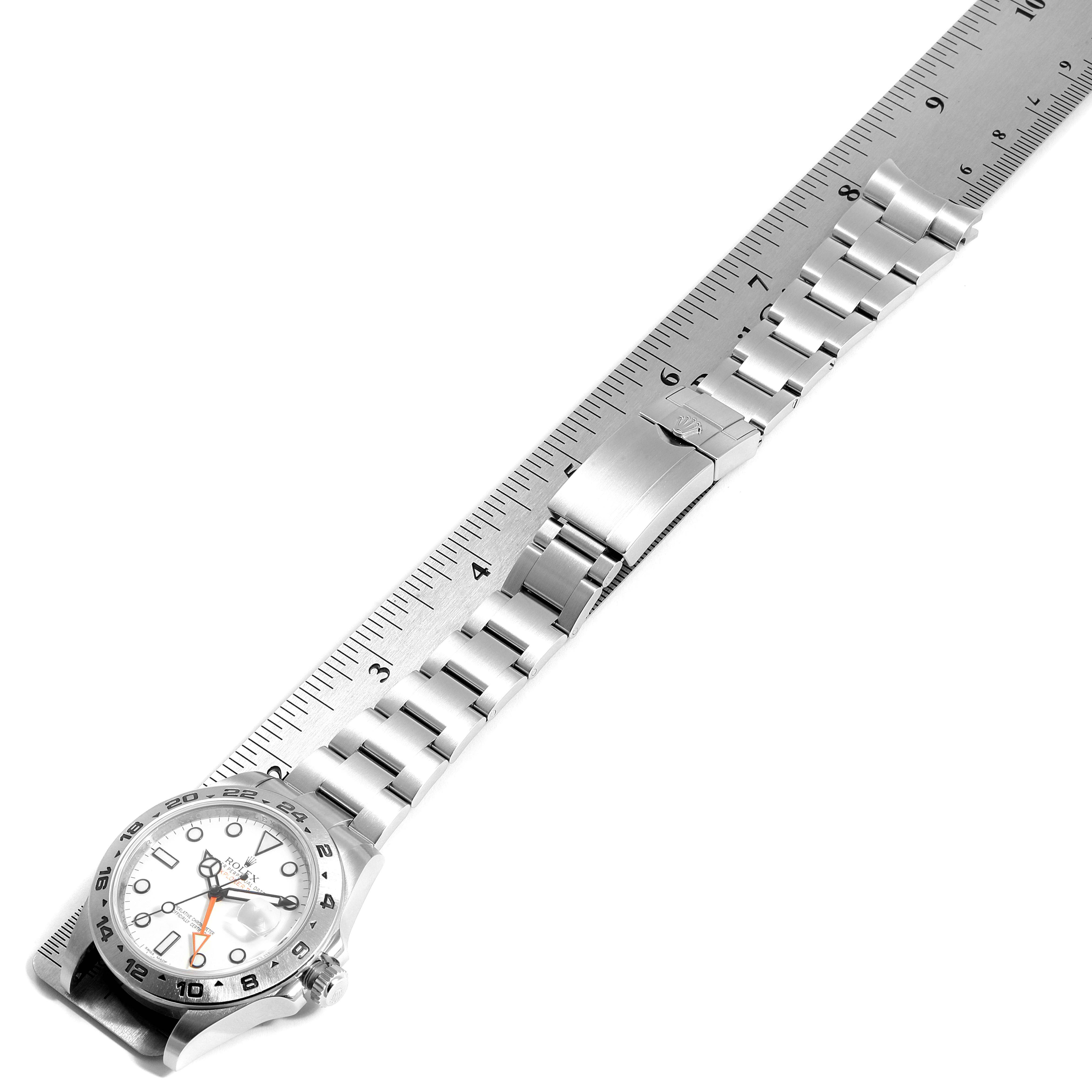 The image shows a Rolex Explorer 216570 Men
s Stainless Steel White Dial 216570 Men
s Stainless Steel White Dial watch with a white dial, laid flat alongside a ruler.