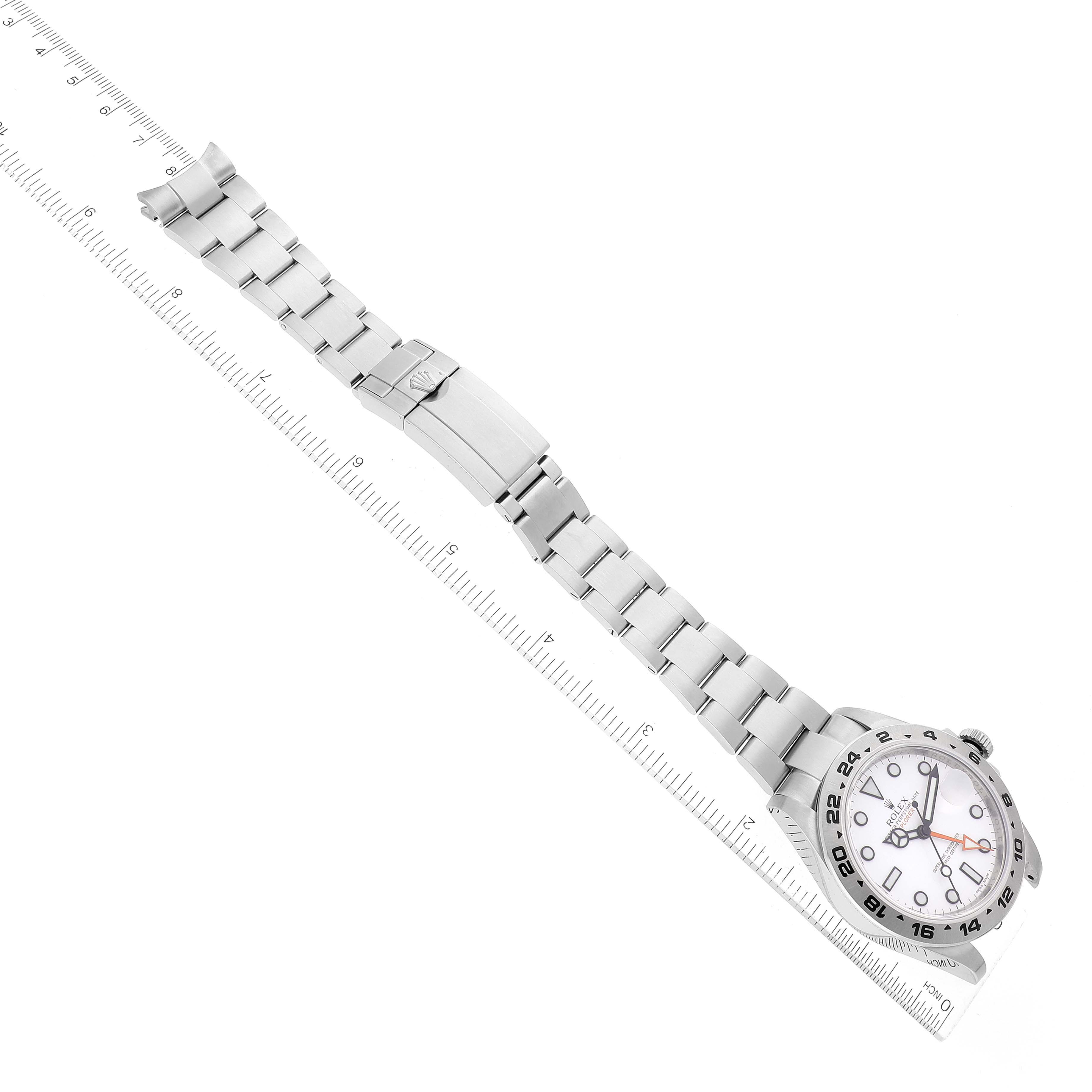 The image shows a top-down view of a Rolex Explorer 216570 Men
s Stainless Steel White Dial 216570 Men
s Stainless Steel White Dial watch with its stainless steel bracelet alongside a ruler for scale.