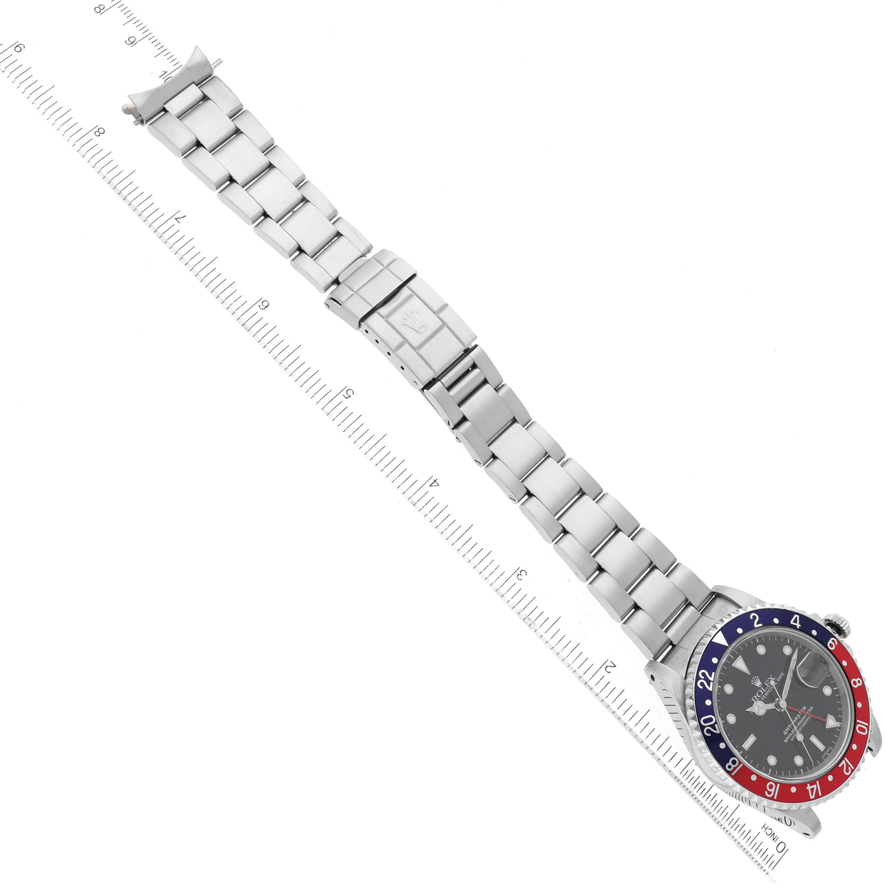 The image shows a Rolex GMT-Master 16700 Men's Stainless Steel Black Dial 16700 Men's Stainless Steel Black Dial watch laid flat on a ruler, displaying the face, bezel, bracelet, and clasp.
