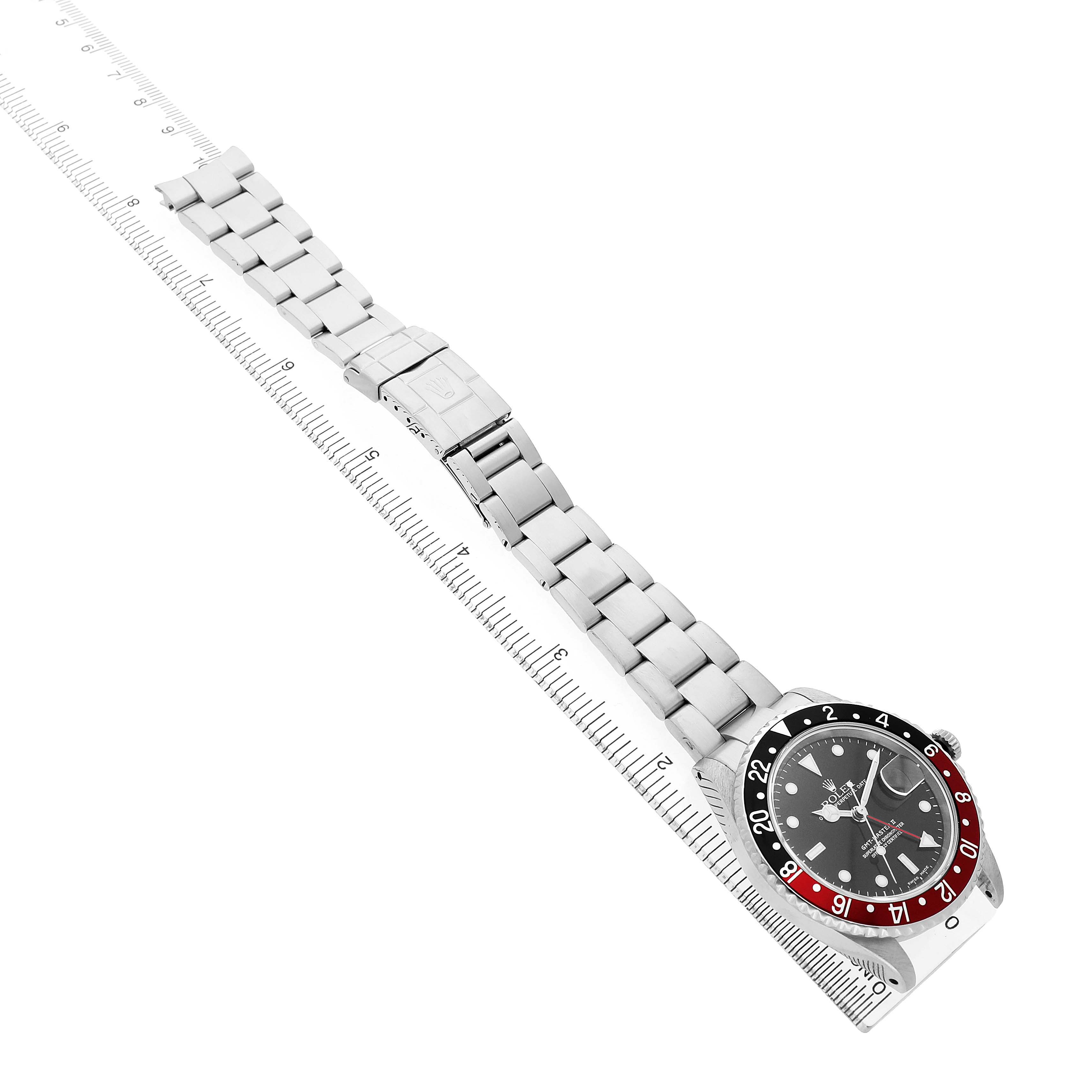 The image shows a top view of a Rolex GMT-Master 16710 Men's Stainless Steel Black Dial watch with a red and black bezel aligned with a ruler for scale.