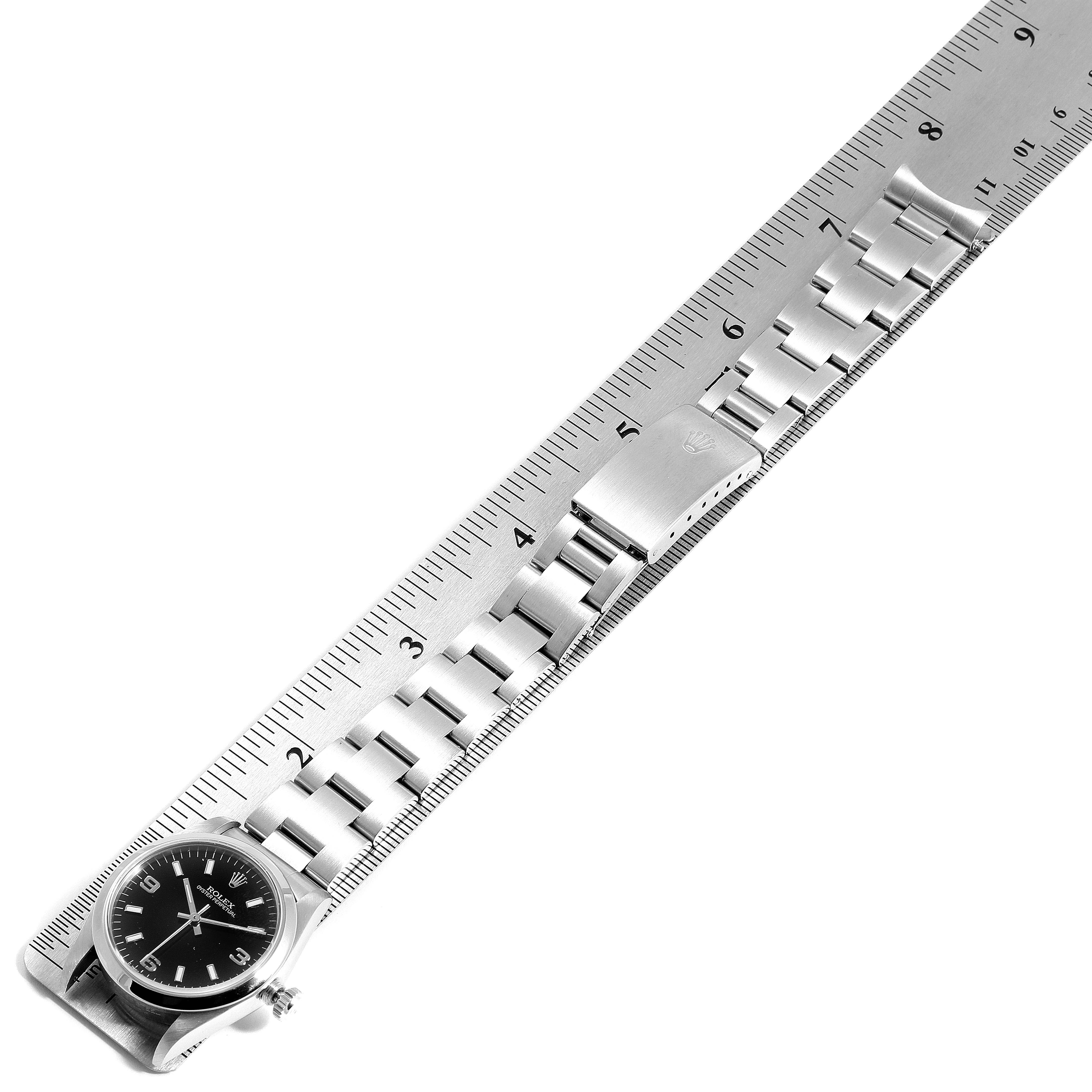 The image shows a Rolex Mid-Size 67480 Women's Stainless Steel Black Dial 67480 Women's Stainless Steel Black Dial watch from a top-down angle, with its bracelet laid out alongside a ruler for measurement.