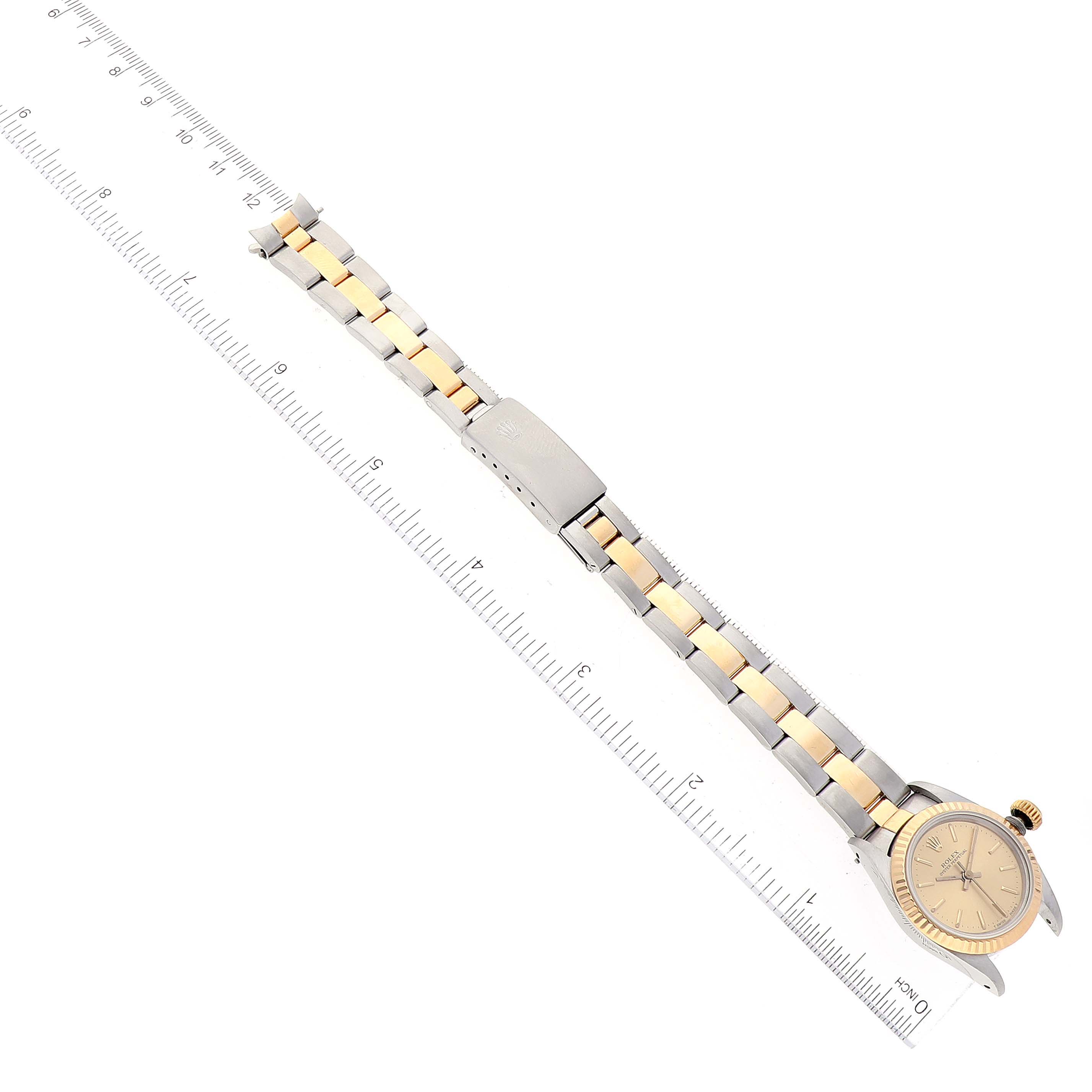 The image shows a Rolex Oyster Perpetual 67193 Women's Steel and Gold (two tone) Champagne Dial 67193 Women's Steel and Gold (two tone) Champagne Dial watch laid flat, displaying its face, case, and two-tone metal strap, with a ruler for scale.