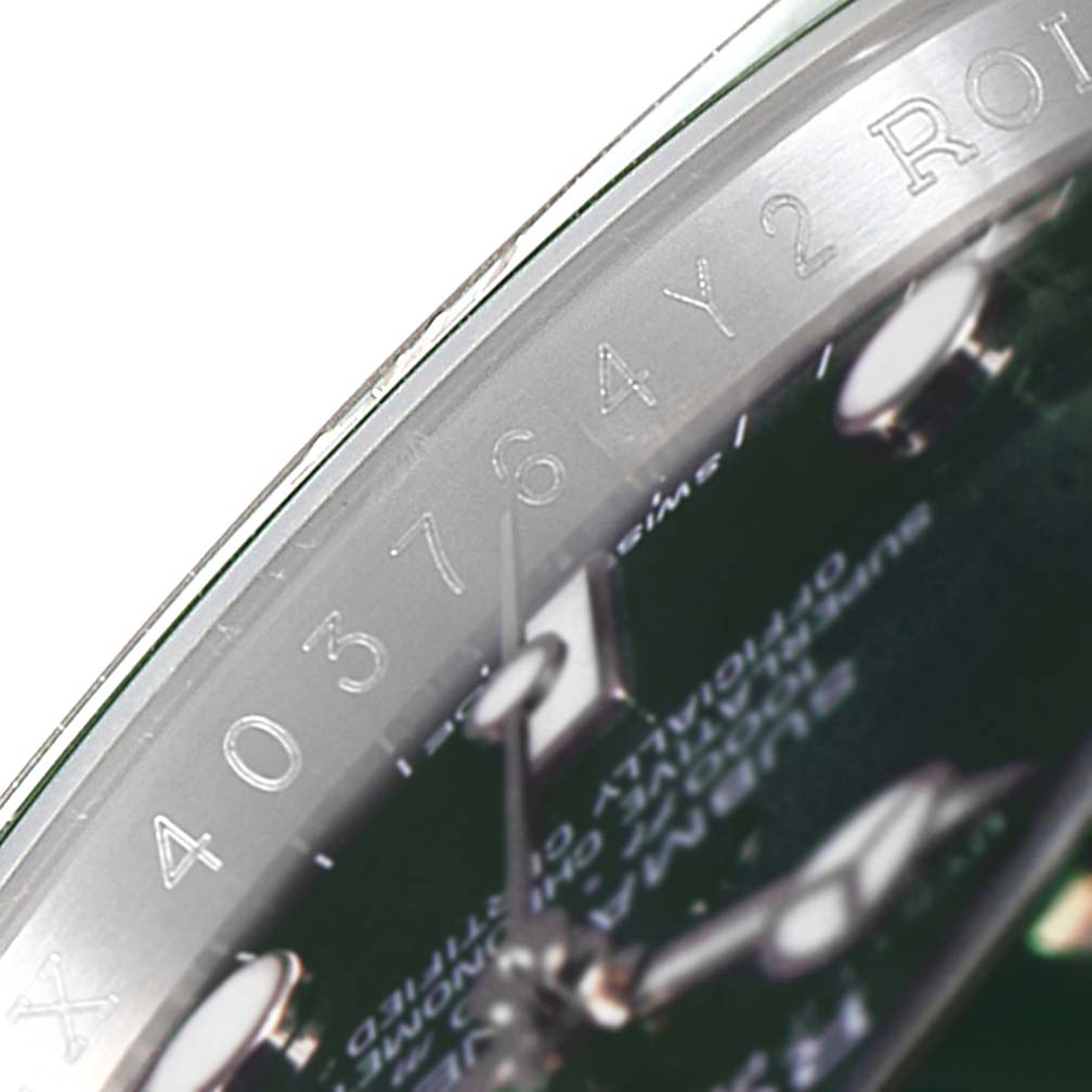 The image displays a close-up of the Rolex Submariner 116610LV Men's Stainless Steel Green Dial 116610LV Men's Stainless Steel Green Dial's dial and part of its bezel with engraved markings.