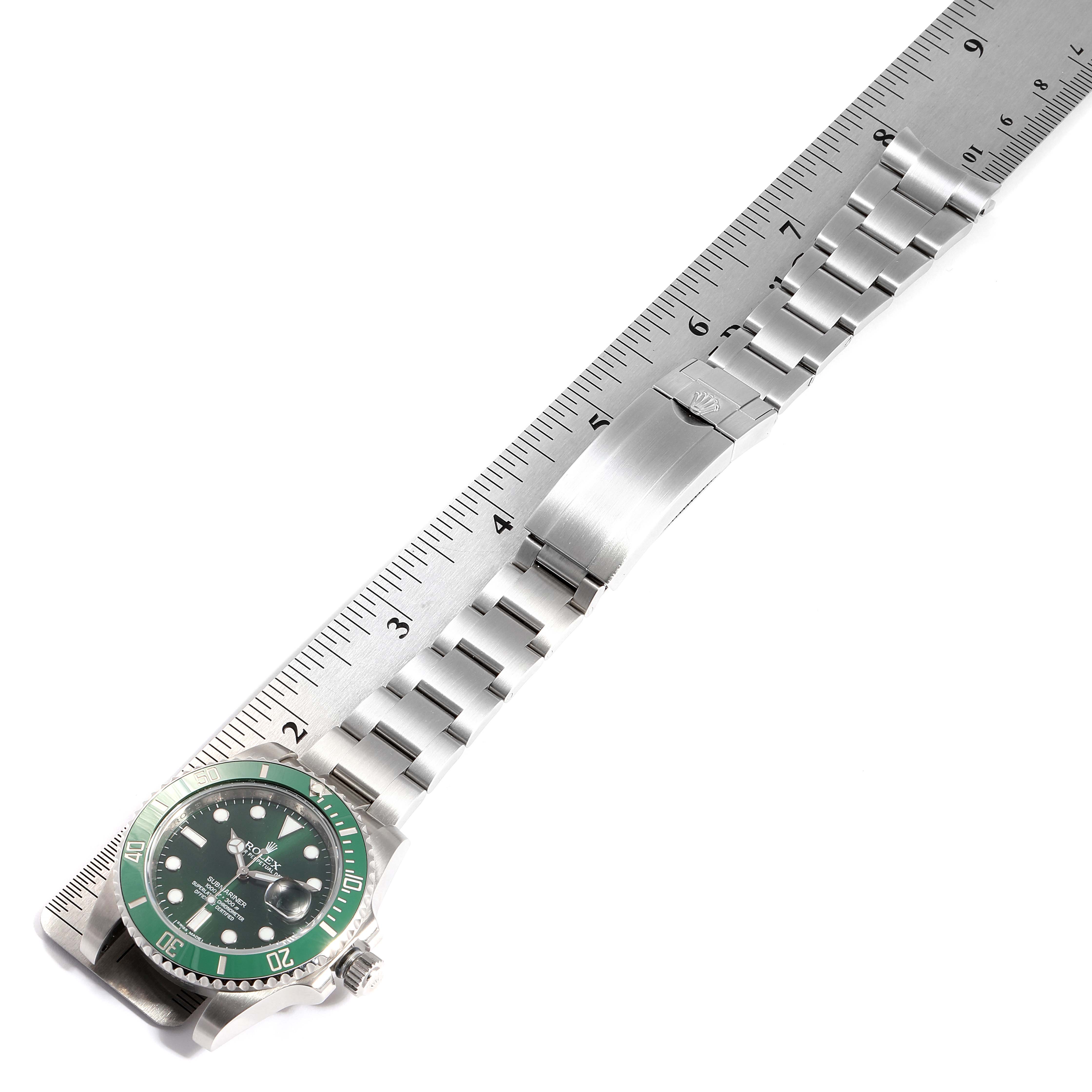 The image shows a Rolex Submariner 116610LV Men's Stainless Steel Green Dial 116610LV Men's Stainless Steel Green Dial watch face-down, displaying its green bezel and metal bracelet with a ruler for scale.
