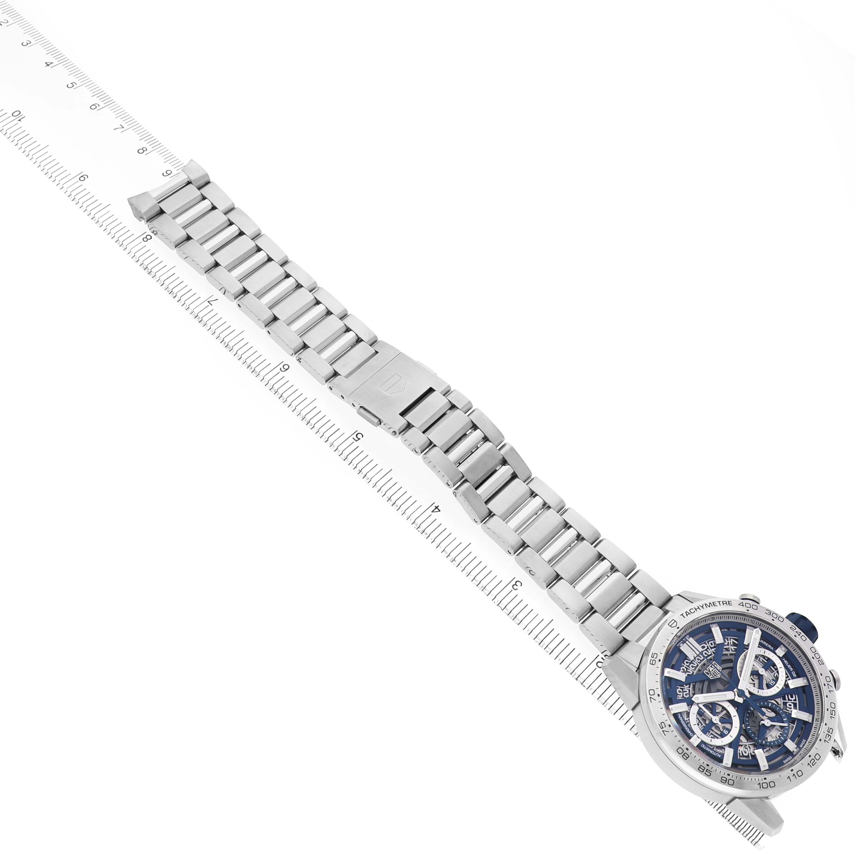 The Tag Heuer Carrera CBG2019.BA0662 Men's Stainless Steel Blue Dial watch is shown at an angle from above, displaying the full bracelet and face alongside a ruler.