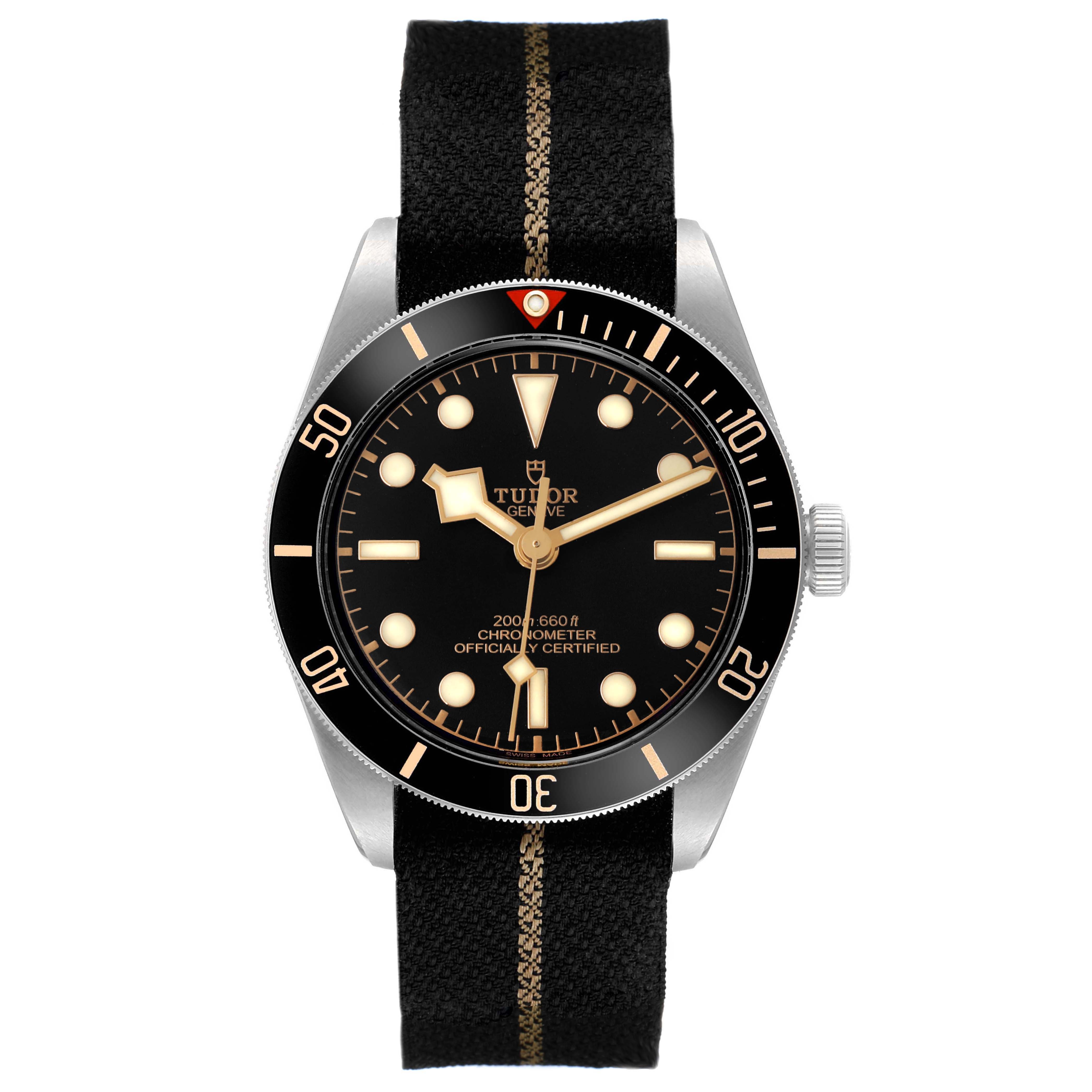 The Tudor Heritage Black Bay 79030 Men's Stainless Steel Black Dial watch is shown from the front, displaying its dial, bezel, and fabric strap.
