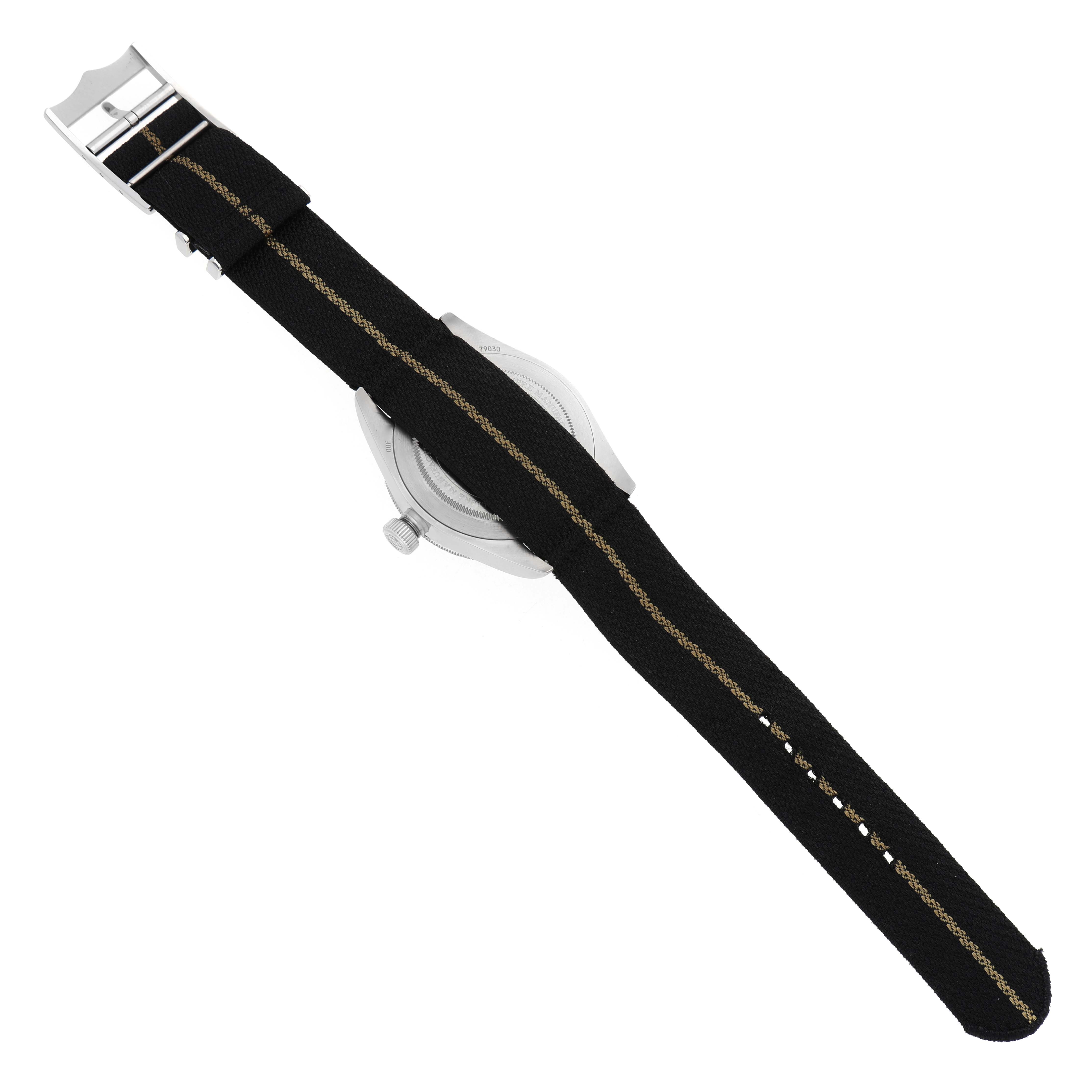 The image shows the back view of a Tudor Heritage Black Bay 79030 Men's Stainless Steel Black Dial watch, highlighting the case, crown, and fabric strap with a clasp.