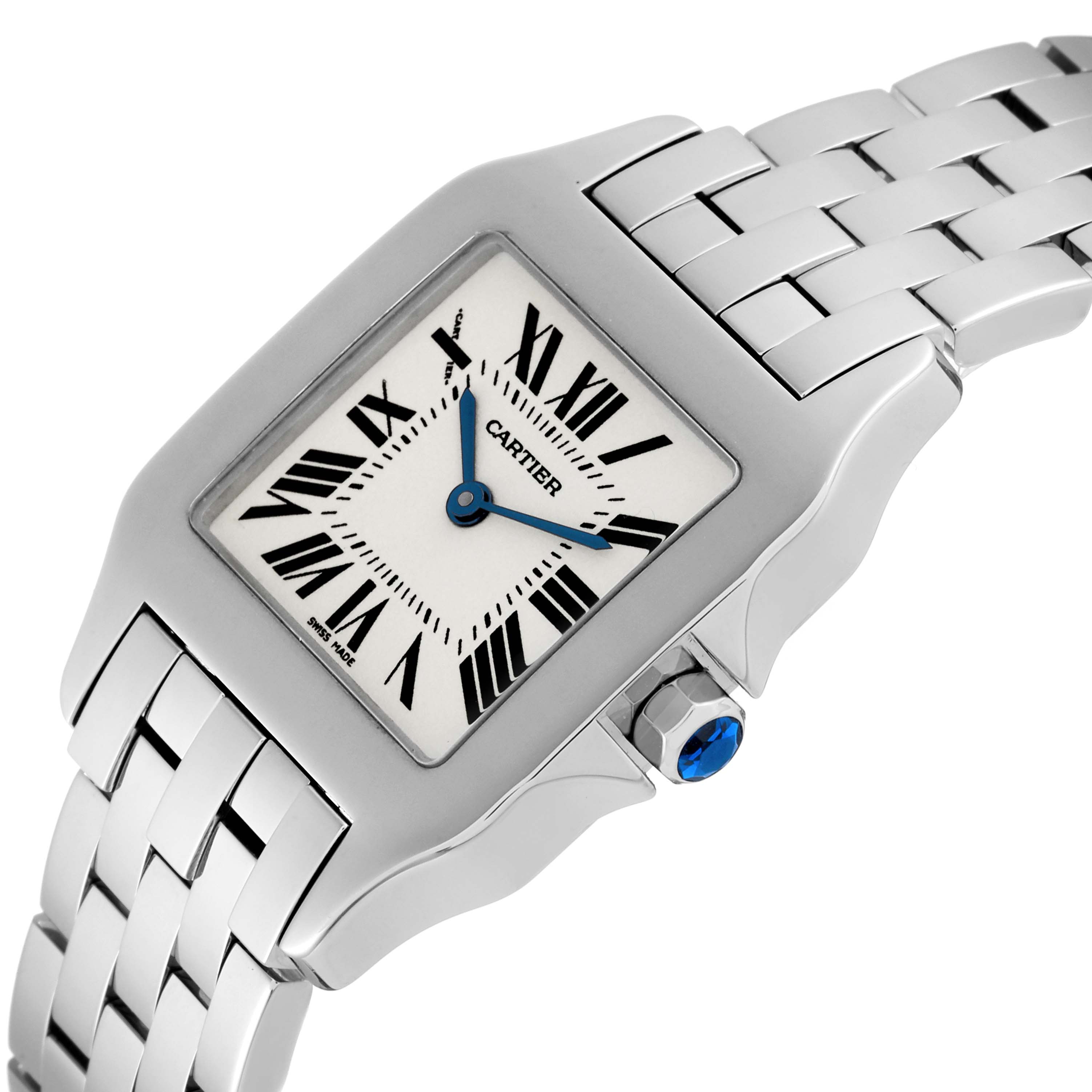 The image shows a Cartier Santos Demoiselle W25065Z5 Women's Stainless Steel Silver Dial W25065Z5 Women's Stainless Steel Silver Dial watch at an angled view, highlighting its face, bezel, bracelet, and crown with a blue gem.
