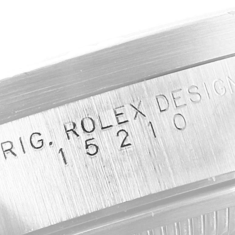 The image shows the side view of a Rolex Date 15210 Men's Stainless Steel Blue Dial 15210 Men's Stainless Steel Blue Dial model, focusing on the engraved serial number and design information.
