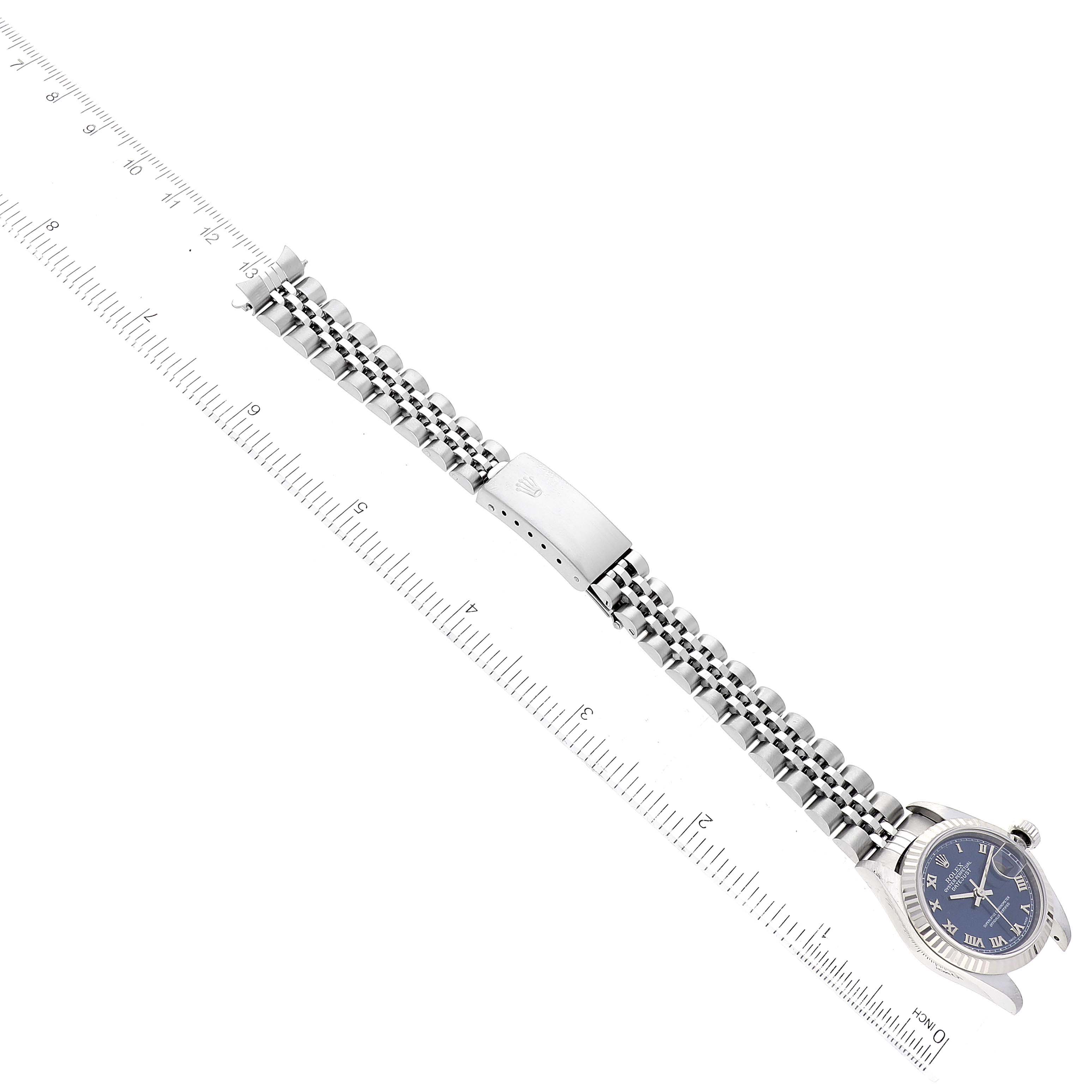 The image shows a top-down view of a Rolex Datejust 79174 Women's Stainless Steel Blue Dial 79174 Women's Stainless Steel Blue Dial watch, including the face, bracelet, and clasp, next to a ruler.