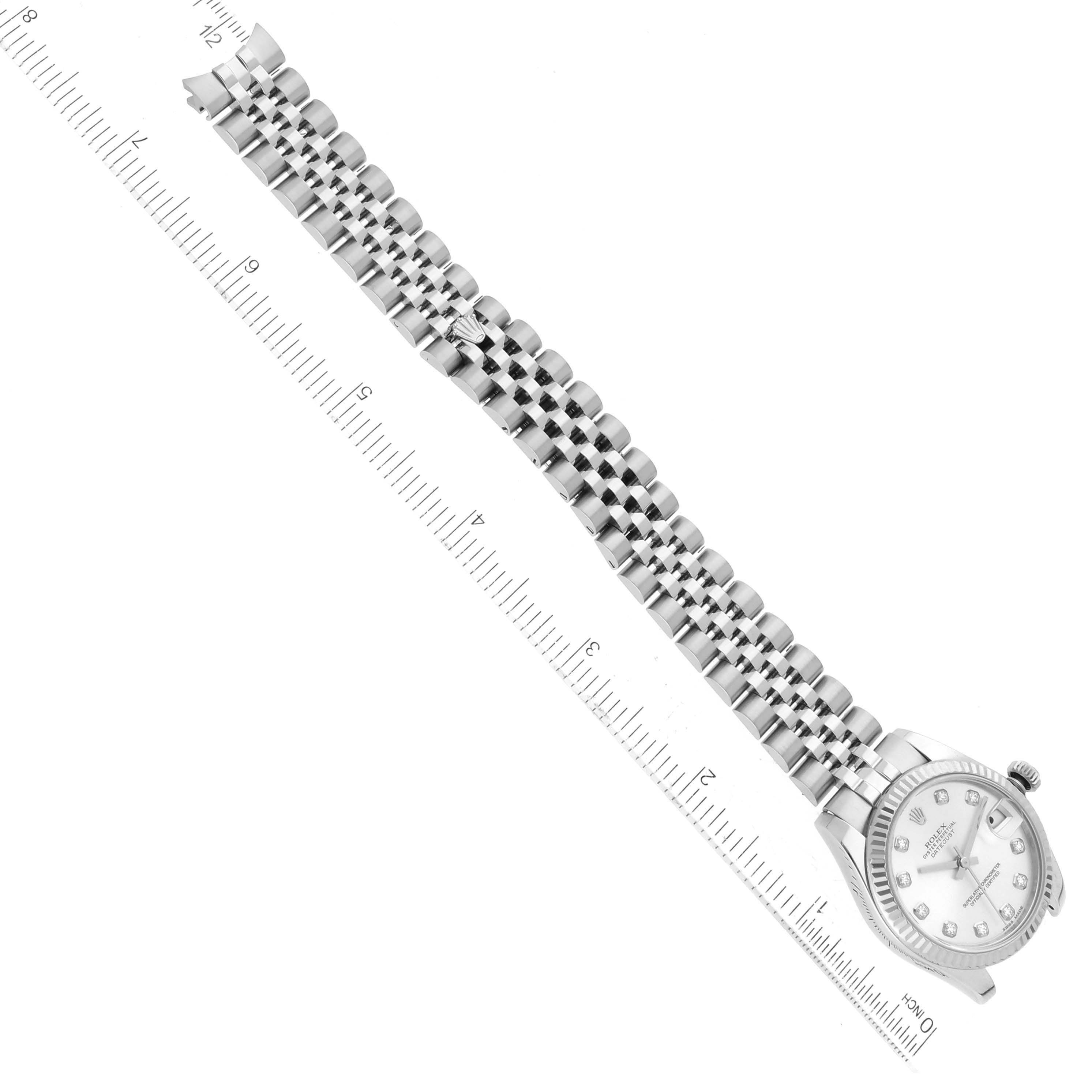 This image shows a top-down view of a Rolex Mid-Size 178274 Women
s Stainless Steel Silver Dial 178274 Women
s Stainless Steel Silver Dial watch with its full bracelet extended alongside a measuring ruler.
