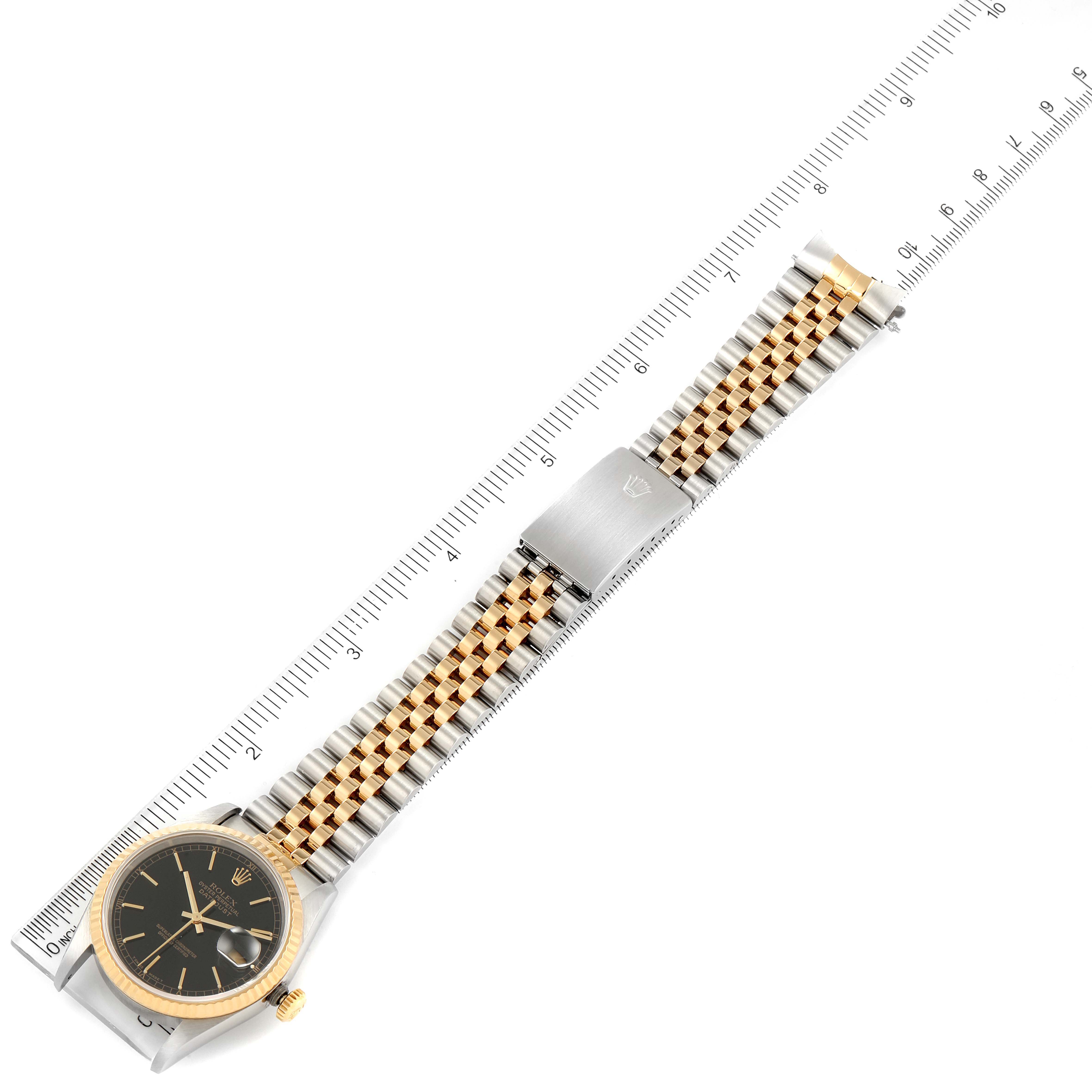 The image shows the watch face and bracelet of a Rolex Datejust 16233 Men's Steel and Gold (two tone) Black Dial 16233 Men's Steel and Gold (two tone) Black Dial model from a top-down angle, with a ruler for scale.