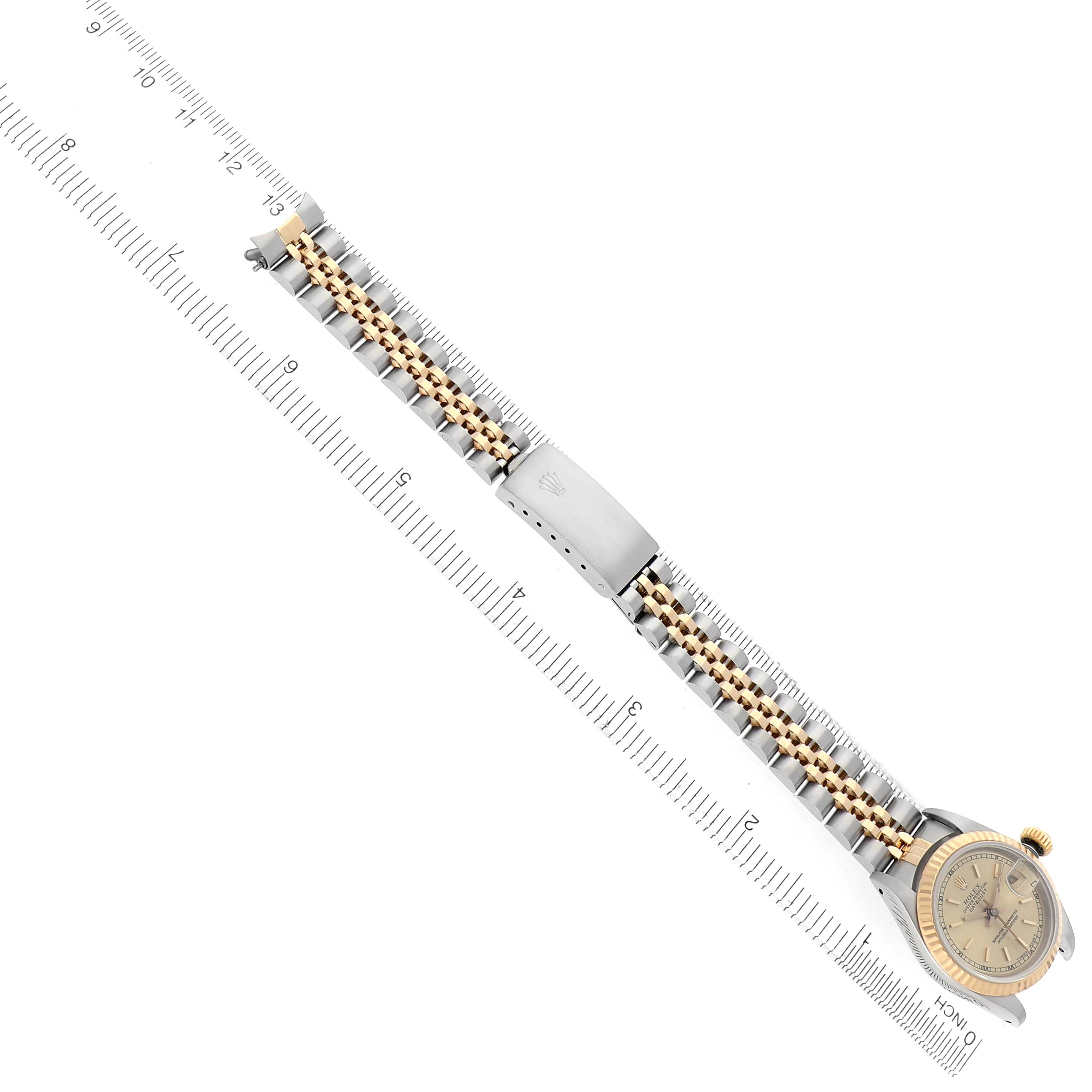 The Rolex Datejust 69173 Women
s Steel and Gold (two tone) Champagne Dial 69173 Women
s Steel and Gold (two tone) Champagne Dial watch is shown from an overhead angle, highlighting the bracelet, clasp, and face alongside a ruler.