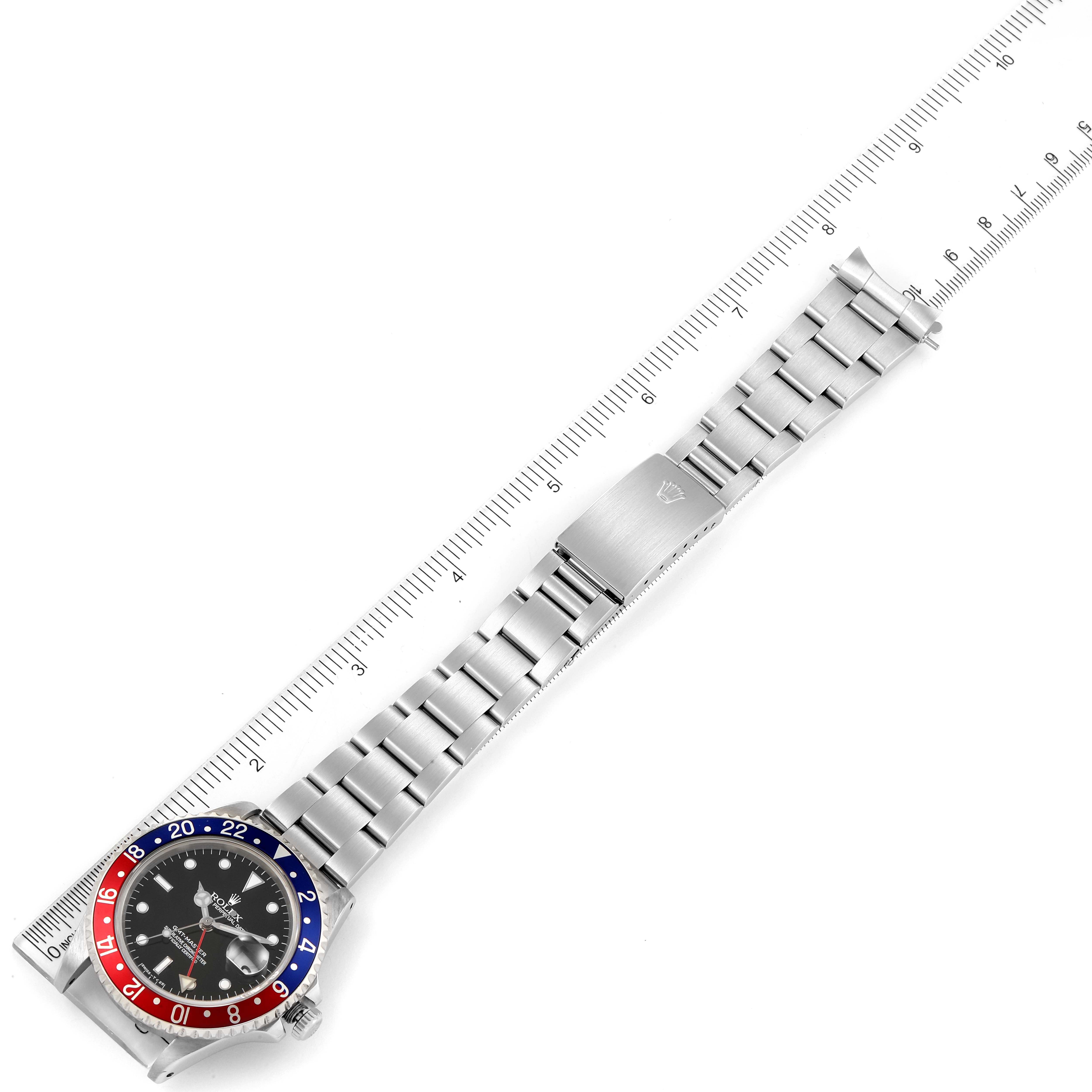 The image shows a top-down view of a Rolex GMT-Master 16700 Men's Stainless Steel Black Dial 16700 Men's Stainless Steel Black Dial watch with a "Pepsi" bezel and a metal bracelet beside a ruler.