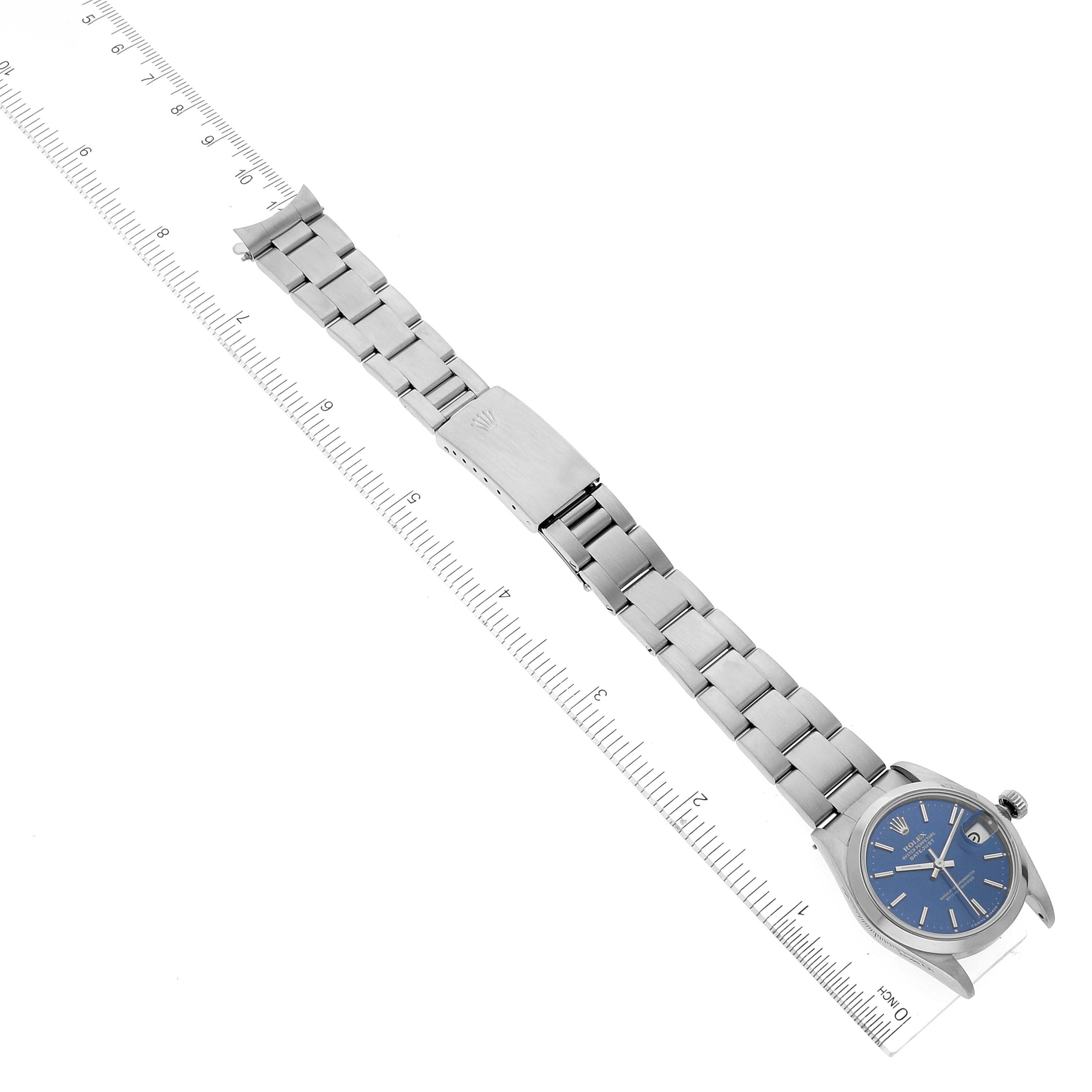 The image shows a Rolex Mid-Size 68240 Women
s Stainless Steel Blue Dial 68240 Women
s Stainless Steel Blue Dial watch laid flat with its bracelet extended next to a ruler for size reference.