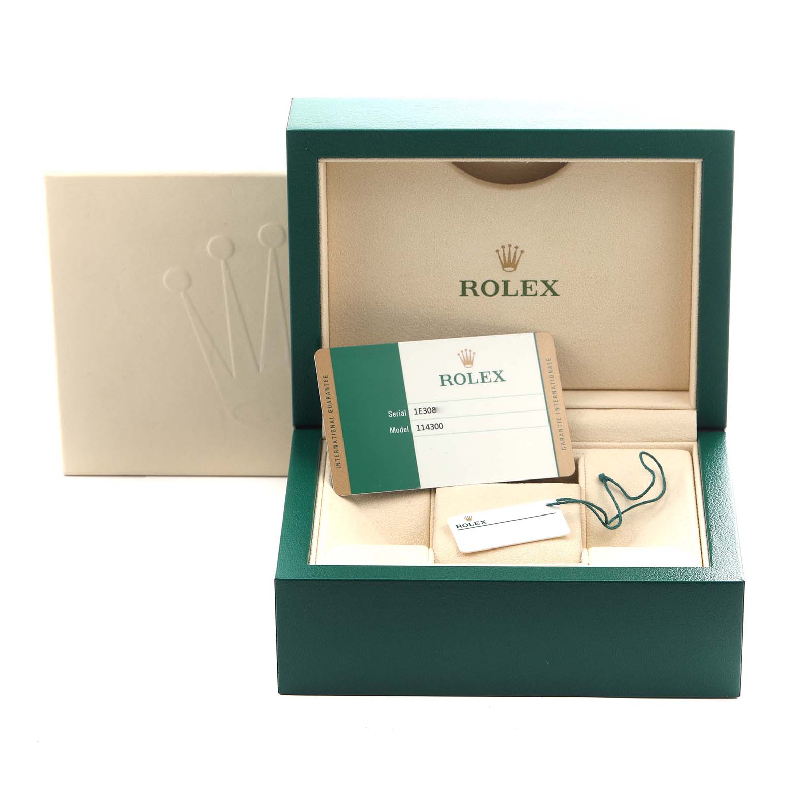 The image shows packaging and accessories for a Rolex Oyster Perpetual 114300 Men's Stainless Steel Blue Dial 114300 Men's Stainless Steel Blue Dial, including a box, card, and tags.