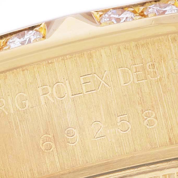 This close-up image shows the engraved serial number and part of the bezel with diamonds of the Rolex President 69258 Women's Yellow Gold Mother of Pearl Dial 69258 Women's Yellow Gold Mother of Pearl Dial model.