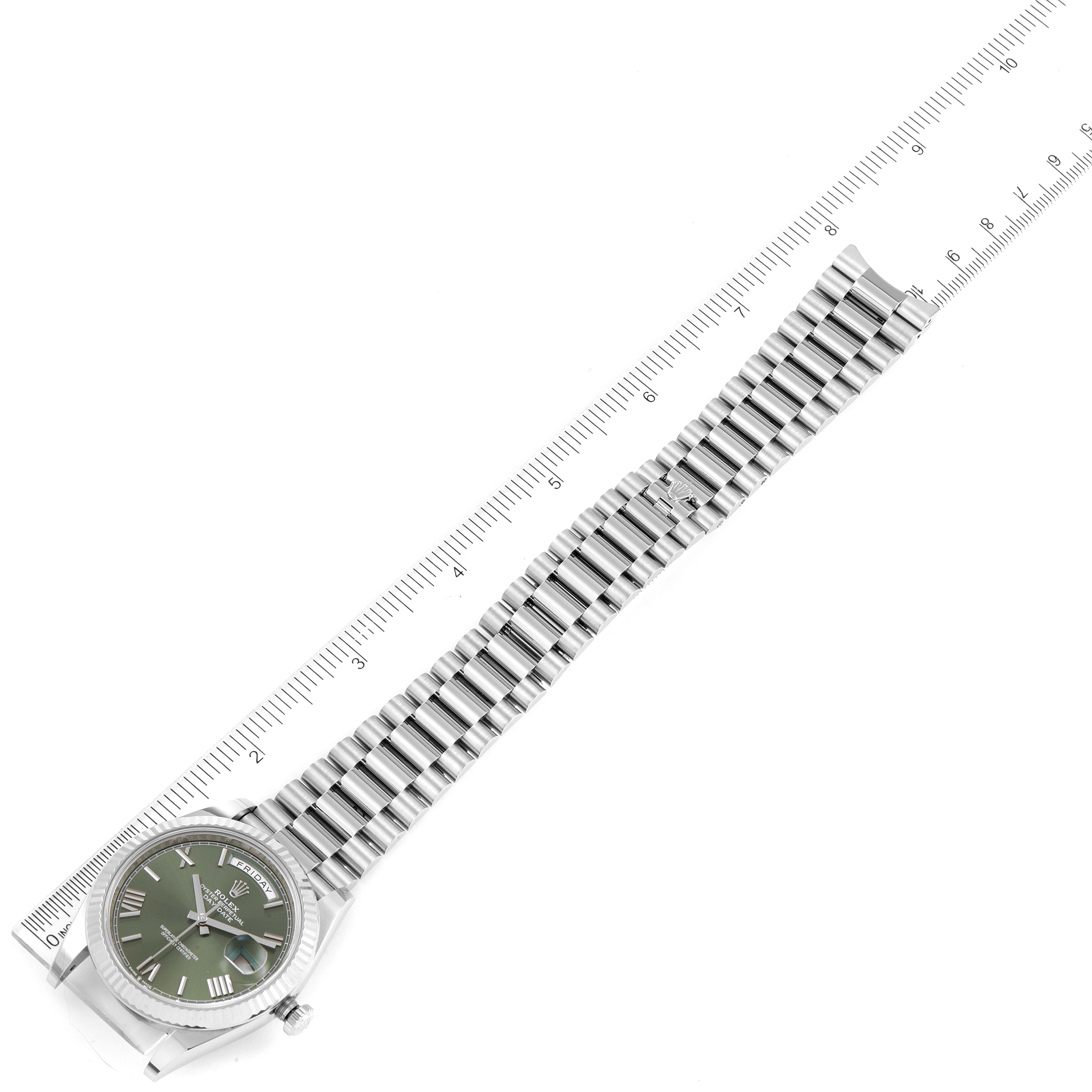 The Rolex President 228239 Men's White Gold Green Dial 228239 Men's White Gold Green Dial model watch is shown from a top-down angle with its full band extended alongside a ruler.