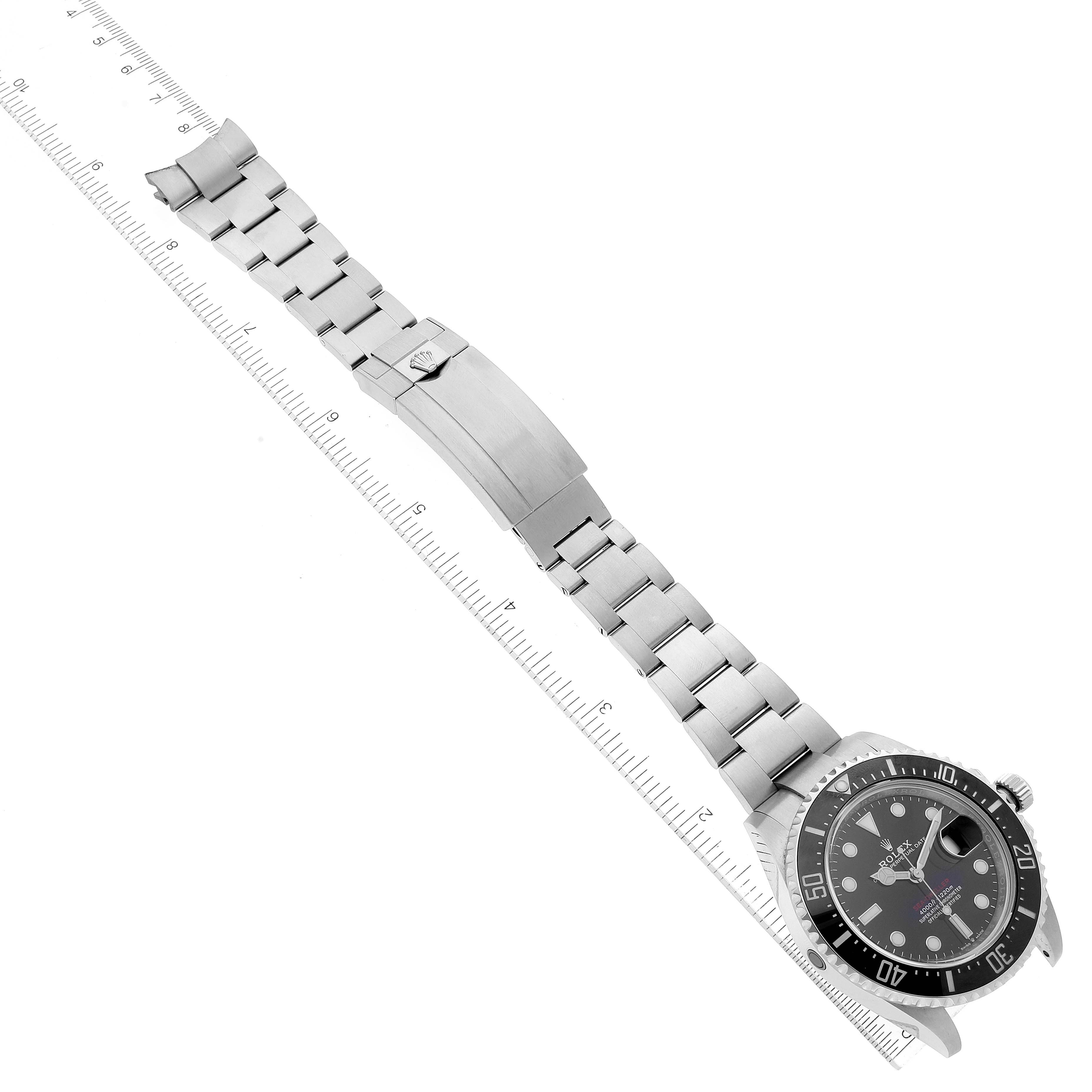 The image shows a Rolex Sea-Dweller 126600 Men
s Stainless Steel Black Dial 126600 Men
s Stainless Steel Black Dial watch laid flat, displaying the face, bezel, crown, and metal bracelet with a measuring scale.