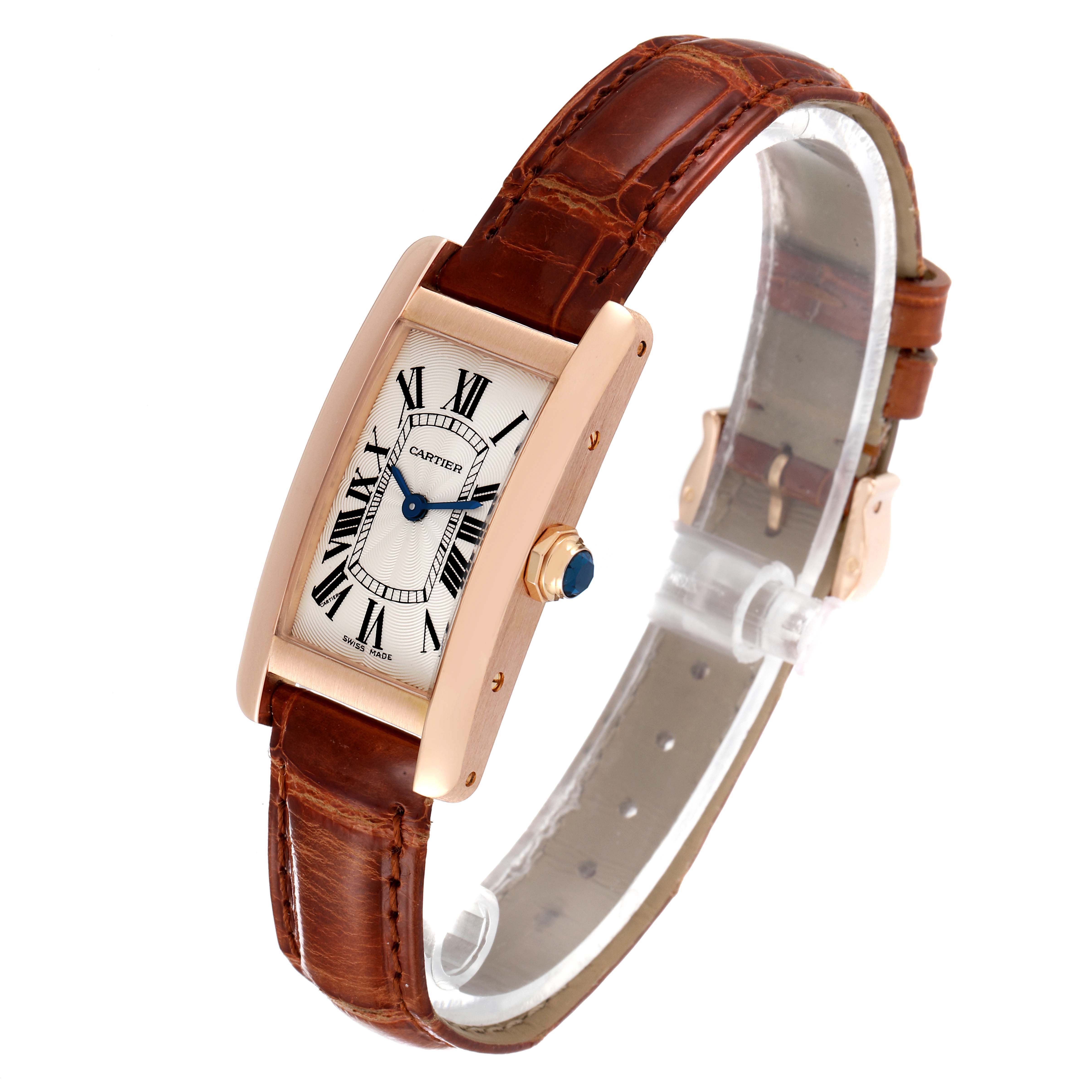 The image shows a Cartier Tank Americaine W2607456 Women's Rose Gold Silver Dial W2607456 Women's Rose Gold Silver Dial watch at a three-quarter angle, highlighting the face, leather strap, and crown with a blue gemstone.