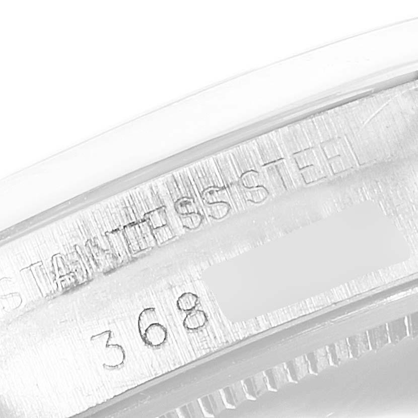 The image shows a close-up of the serial number and "stainless steel" engraving on the side of a Rolex Vintage Collection 6694 Men's Stainless Steel Black Dial 6694 Men's Stainless Steel Black Dial watch case.