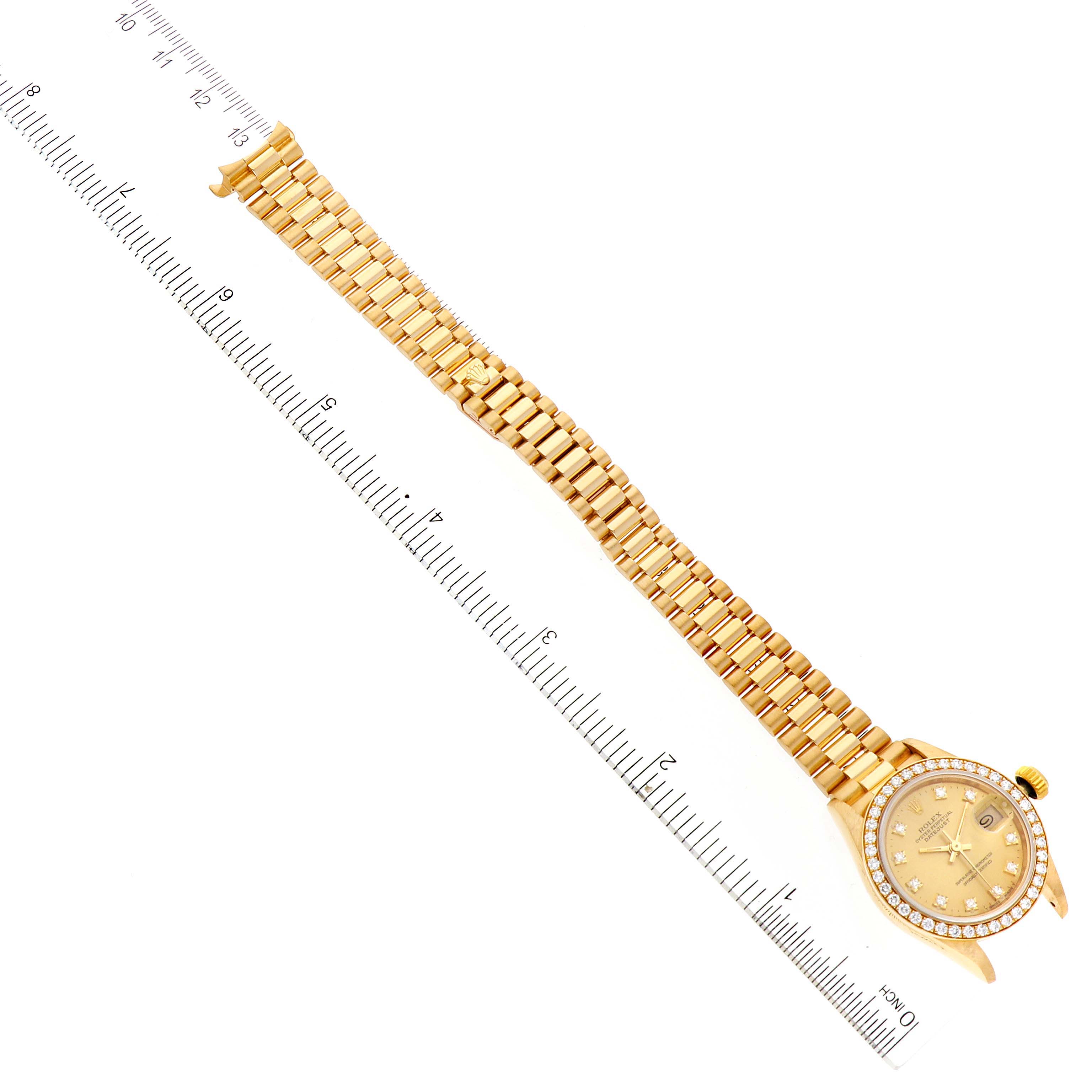 The image shows a Rolex President 69138 Women
s Yellow Gold Champagne Dial 69138 Women
s Yellow Gold Champagne Dial watch laid flat, with its face, bezel, and bracelet visible, next to a ruler for scale.