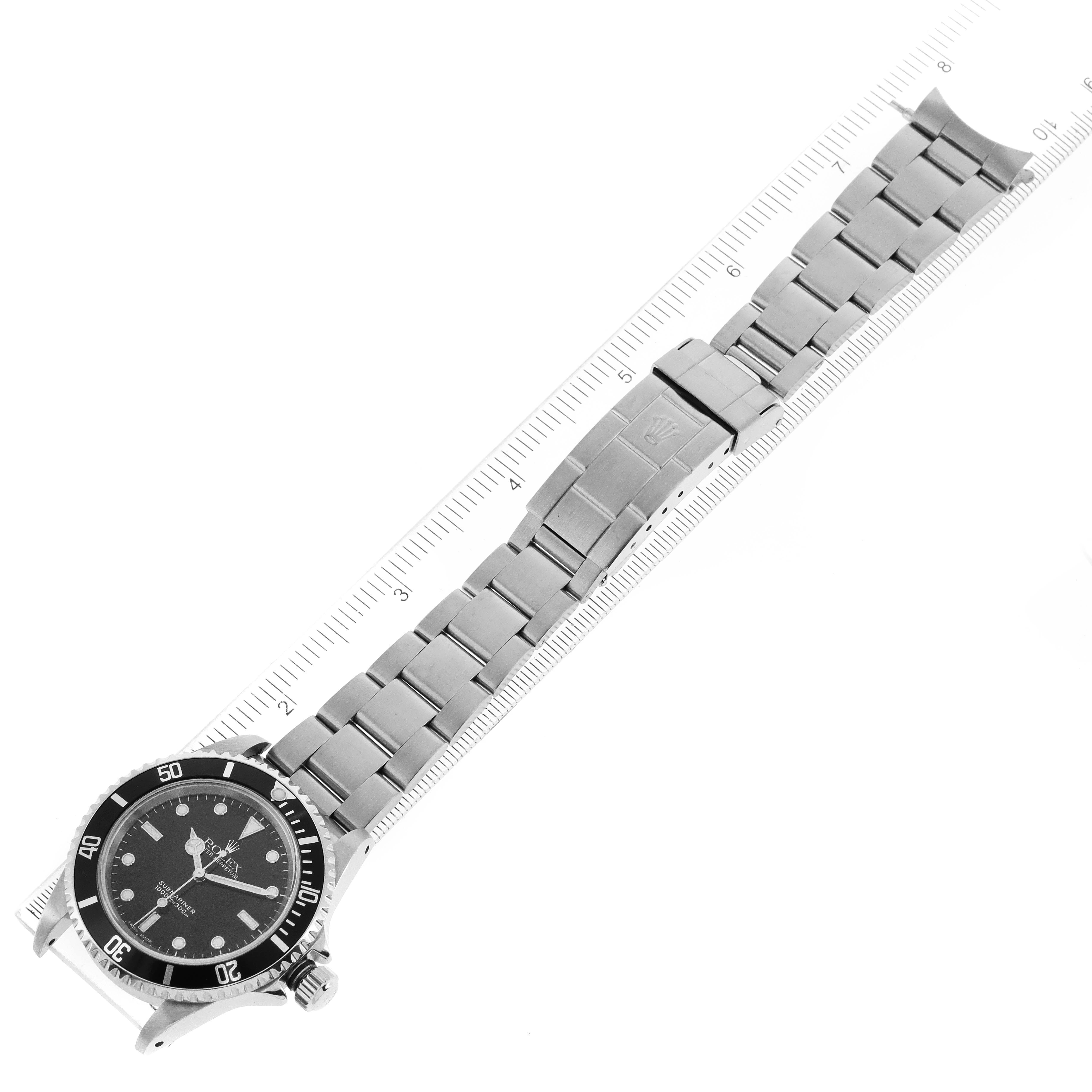 The Rolex Submariner 14060 Men
s Stainless Steel Black Dial 14060 Men
s Stainless Steel Black Dial watch is displayed flat on a ruler, showing the black dial, bezel, and stainless steel bracelet in a top-down view.