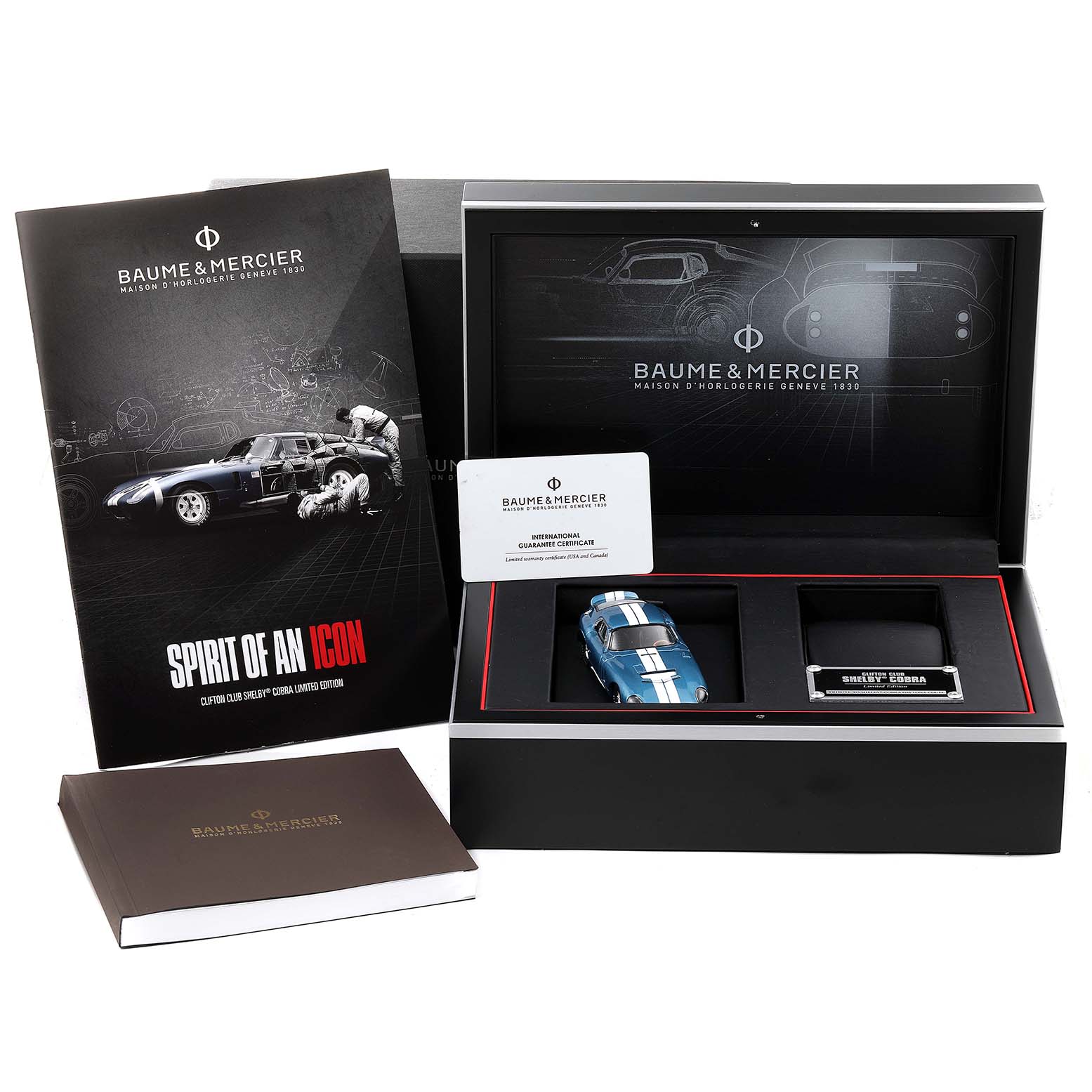 The image shows the packaging and accessories for the Baume & Mercier Clifton M0A10342 Men's Stainless Steel Silver Dial M0A10342 Men's Stainless Steel Silver Dial model, including a booklet, a miniature car, and a warranty card.