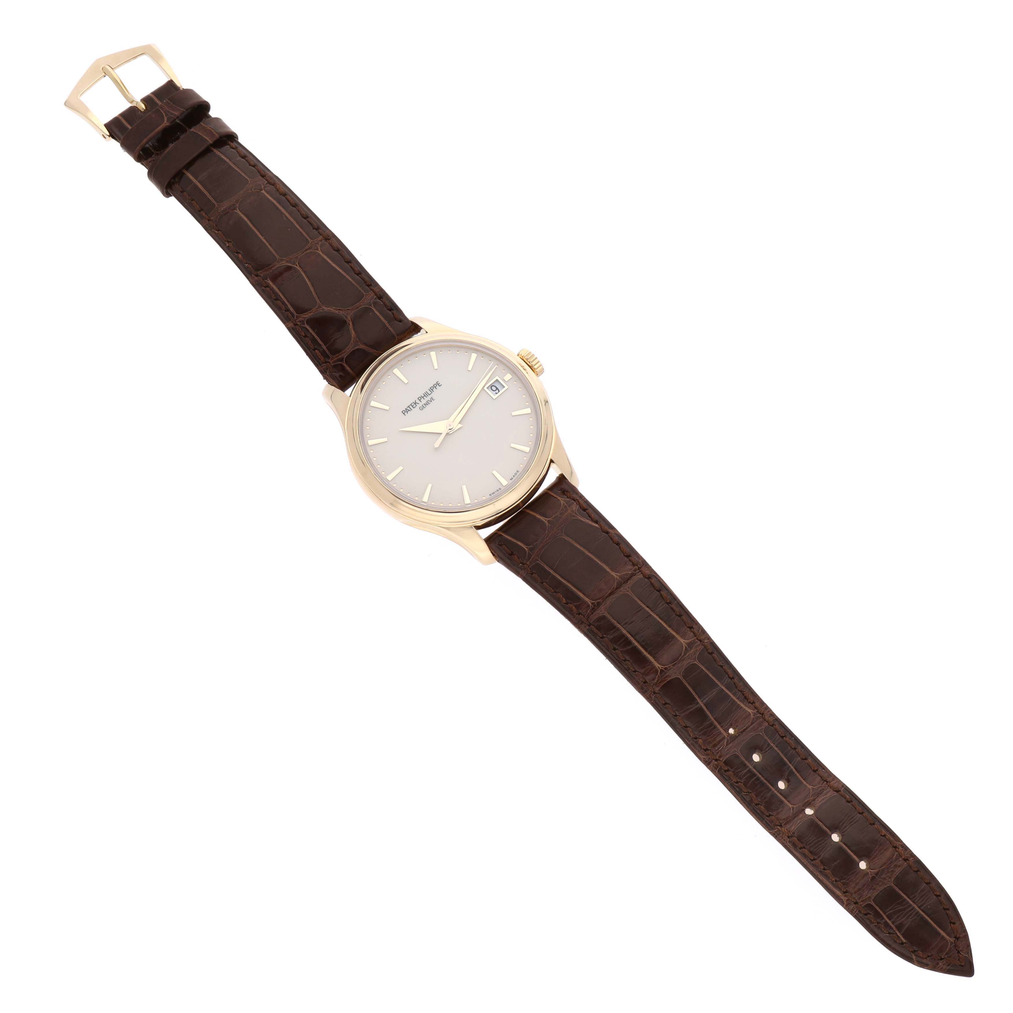 The Patek Philippe Calatrava 5227J Men's Yellow Gold White Dial watch is shown from a top view, displaying the face, dial, crown, and brown leather strap.