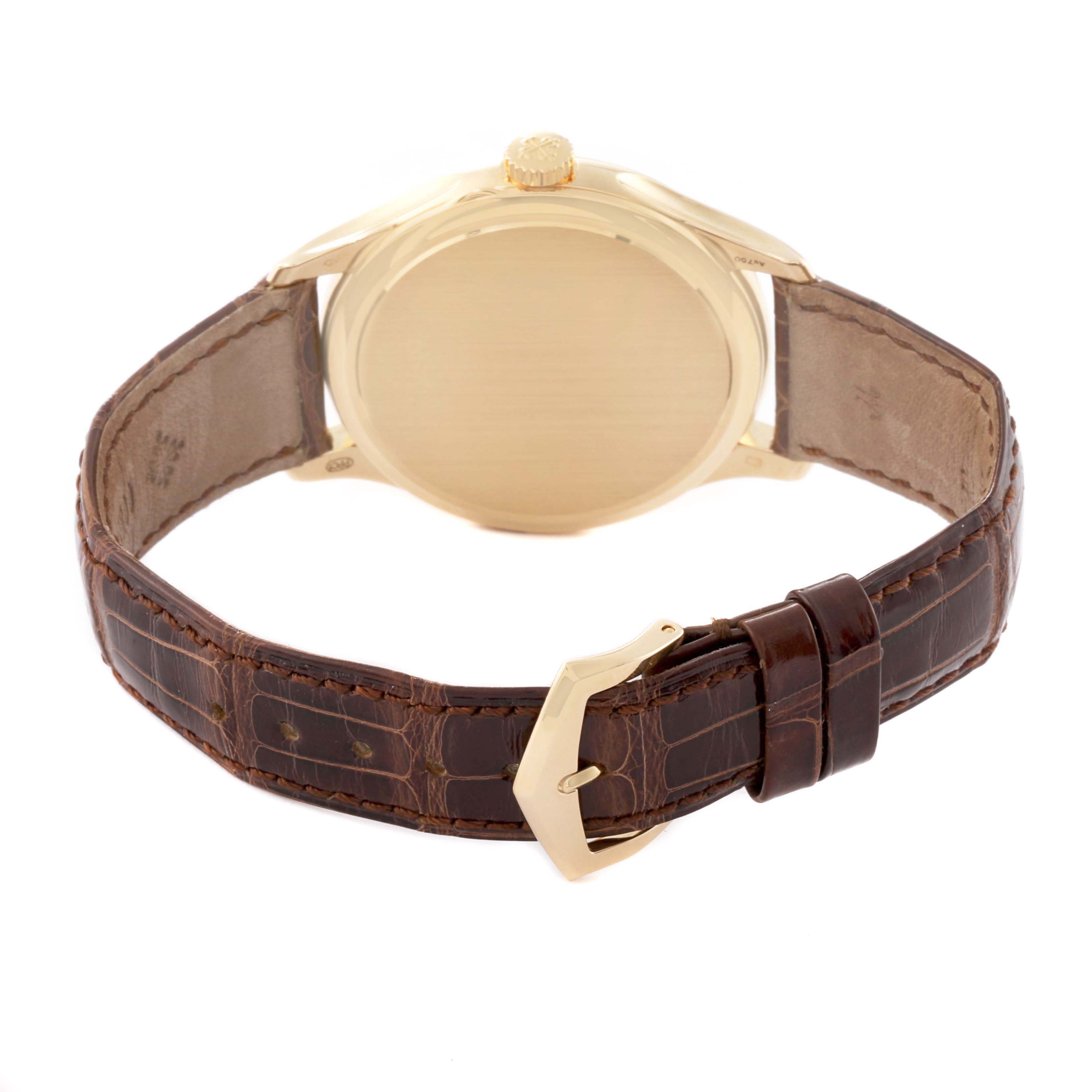 The image shows the back view of a Patek Philippe Calatrava 5227J Men's Yellow Gold White Dial watch, highlighting the case, crown, and brown leather strap.
