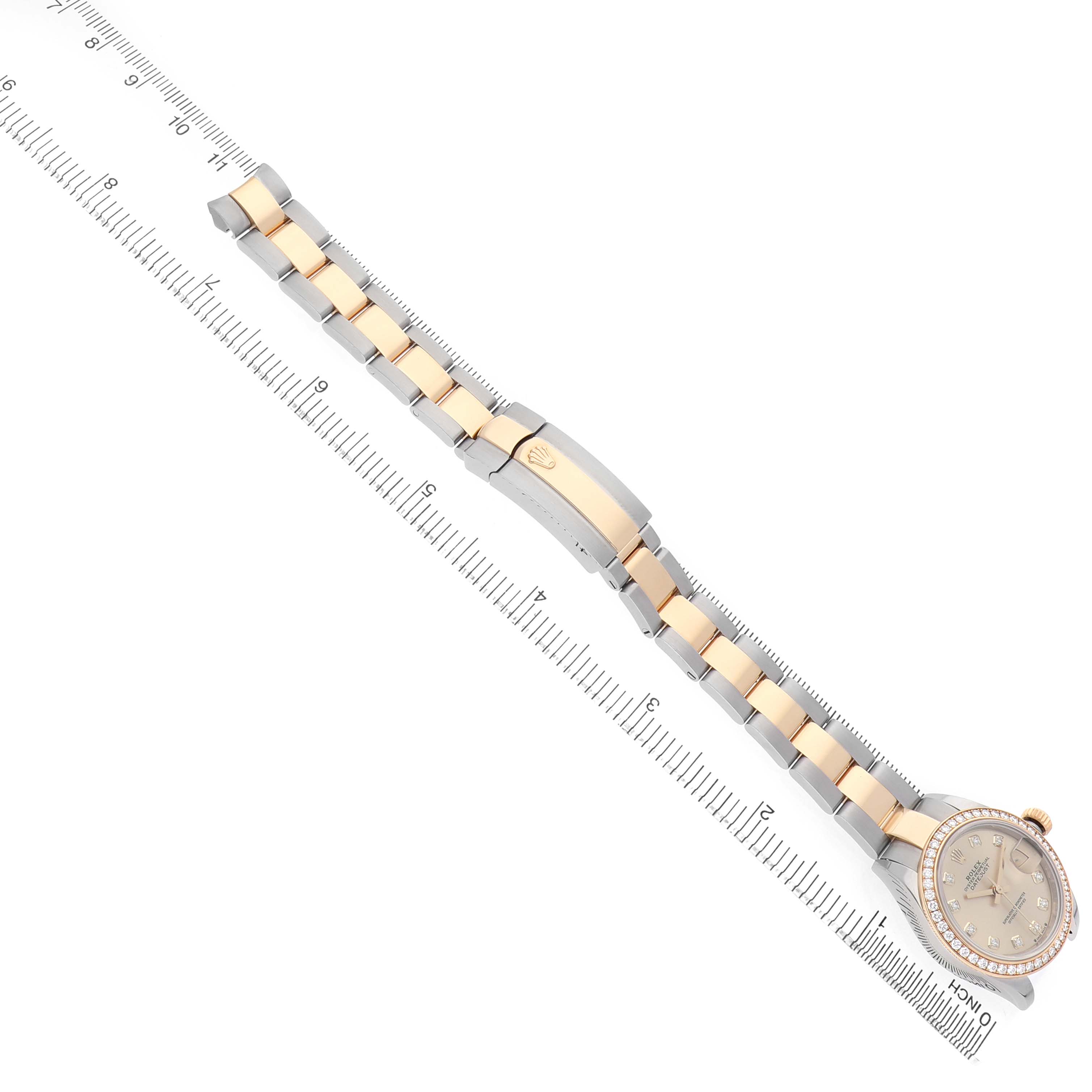 The Rolex Datejust 279383 Women's Stainless Steel Champagne Dial watch is shown at an angle displaying its bracelet, clasp, and face, with a ruler for size reference.