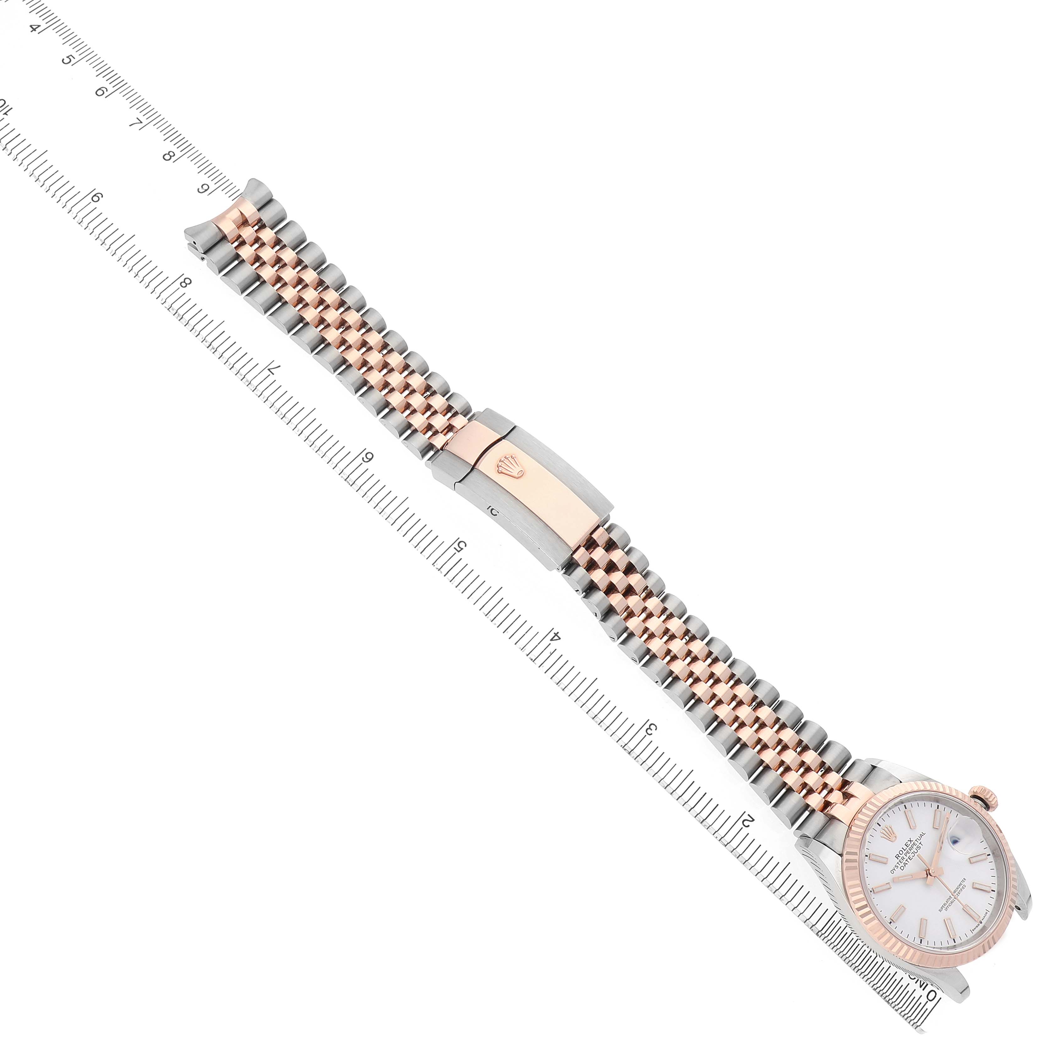 The Rolex Datejust 126231 Men's Steel and Gold (two tone) White Dial watch is shown at a diagonal angle, featuring the full dial, case, bracelet, and clasp alongside a ruler.