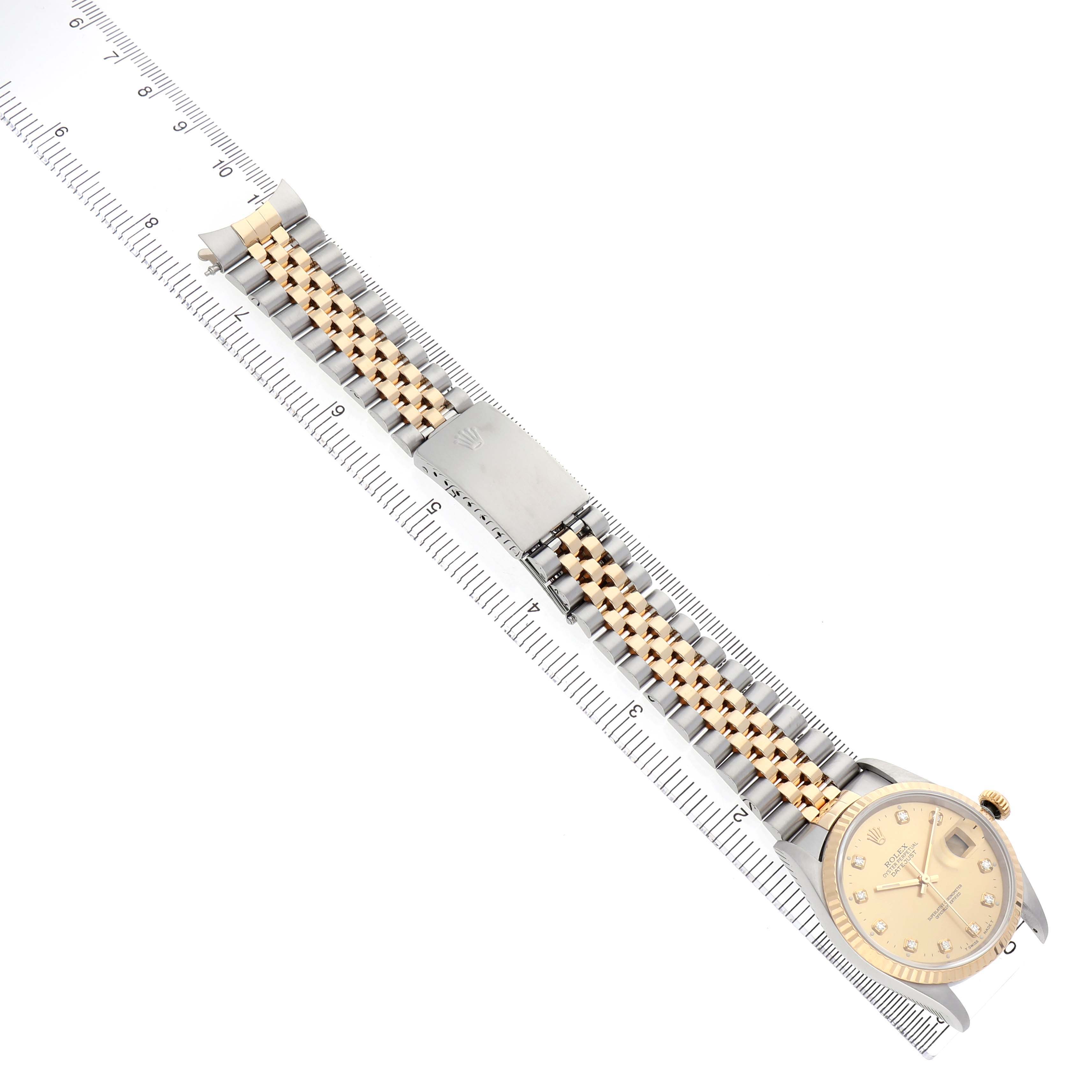 The Rolex Datejust 16233 Men's Steel and Gold (two tone) Champagne Dial watch is shown laid flat, highlighting the face and the two-tone jubilee bracelet aligned with a ruler.