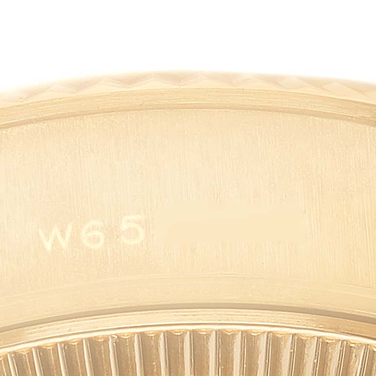 This close-up image shows the fluted bezel and part of the case of a Rolex President 69178 Women
s Yellow Gold Champagne Dial 69178 Women
s Yellow Gold Champagne Dial model watch, highlighting a serial number.