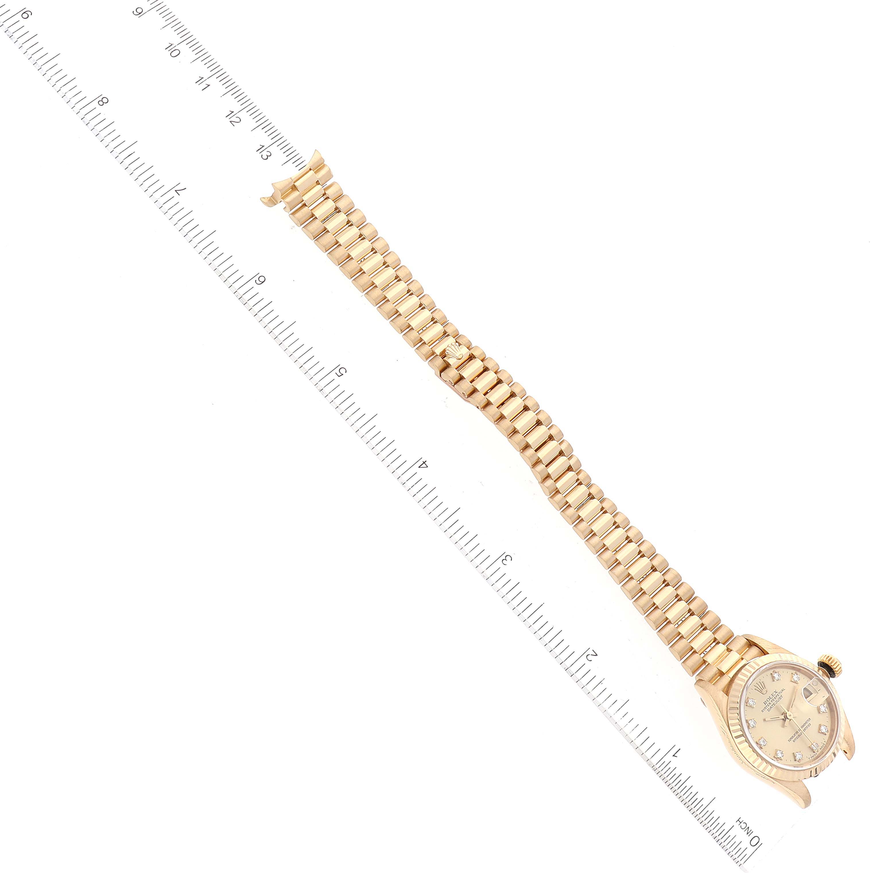 The image shows the watch face and bracelet strap of a Rolex President 69178 Women
s Yellow Gold Champagne Dial 69178 Women
s Yellow Gold Champagne Dial model watch, extended and aligned with a ruler.
