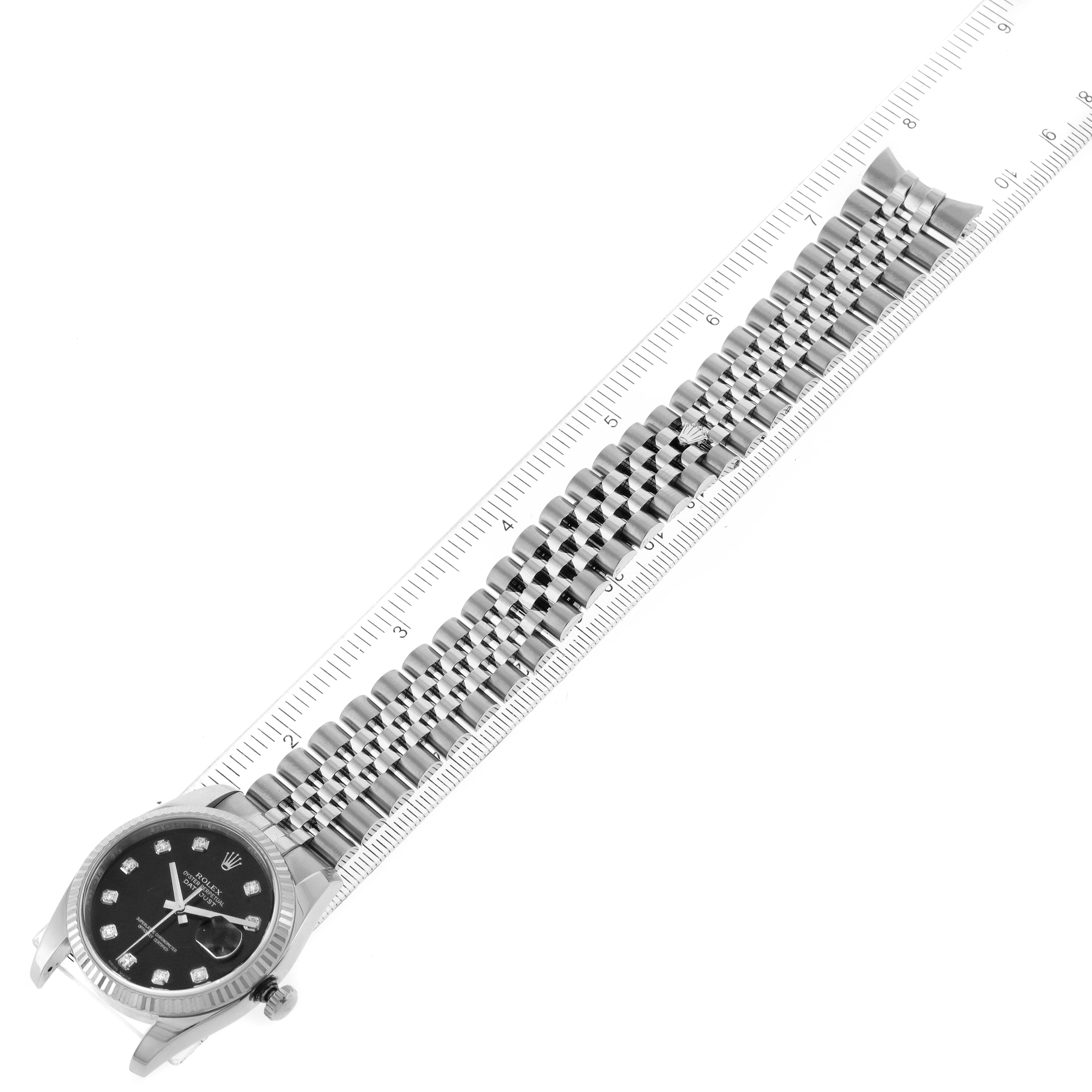 The image shows the Rolex Datejust 116234 Men
s Stainless Steel Black Dial 116234 Men
s Stainless Steel Black Dial watch lying flat next to a ruler, highlighting the face, bezel, and bracelet.