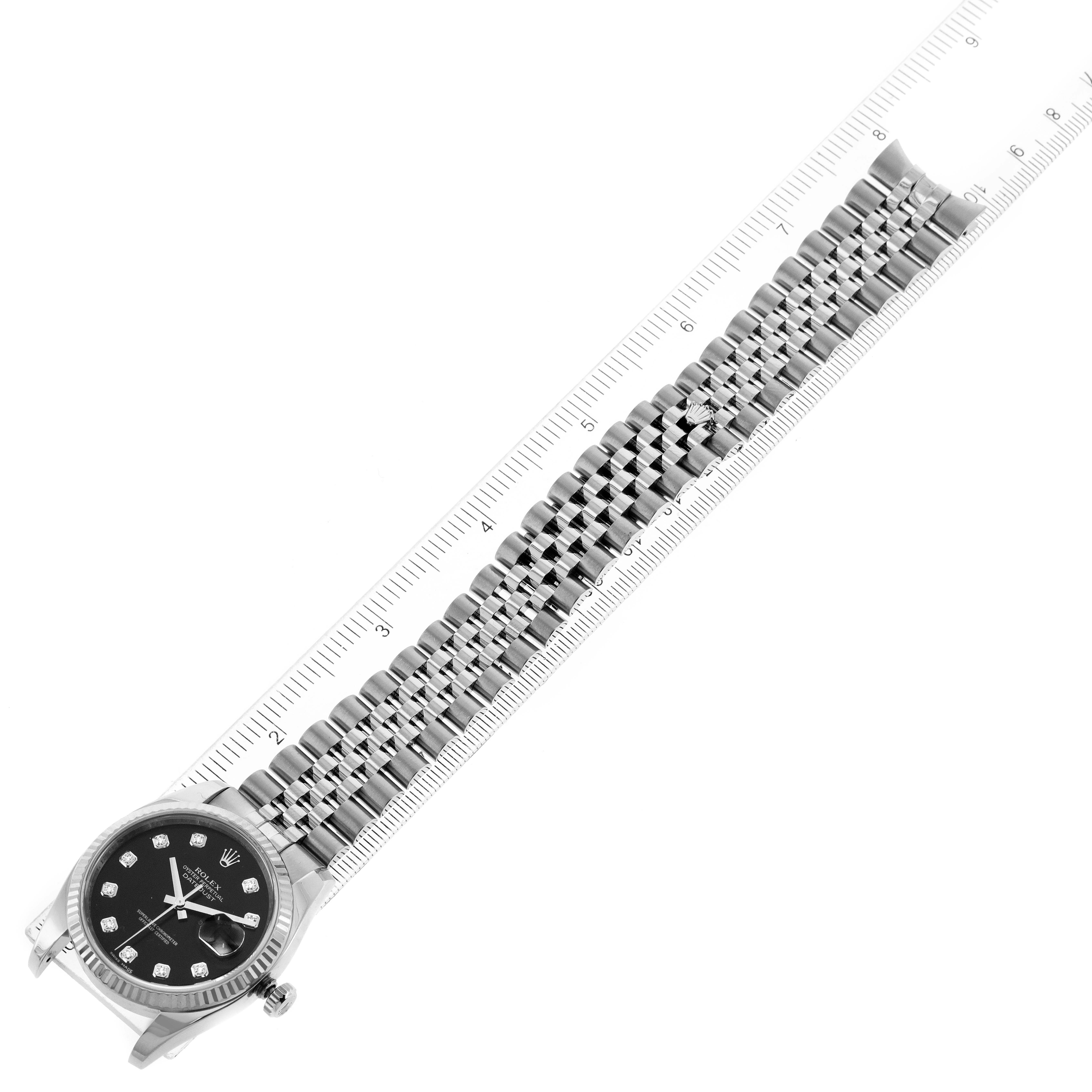 The image shows a top-down view of a Rolex Datejust 116234 Men
s Stainless Steel Black Dial 116234 Men
s Stainless Steel Black Dial watch, featuring its black dial and metal band measured against a ruler.