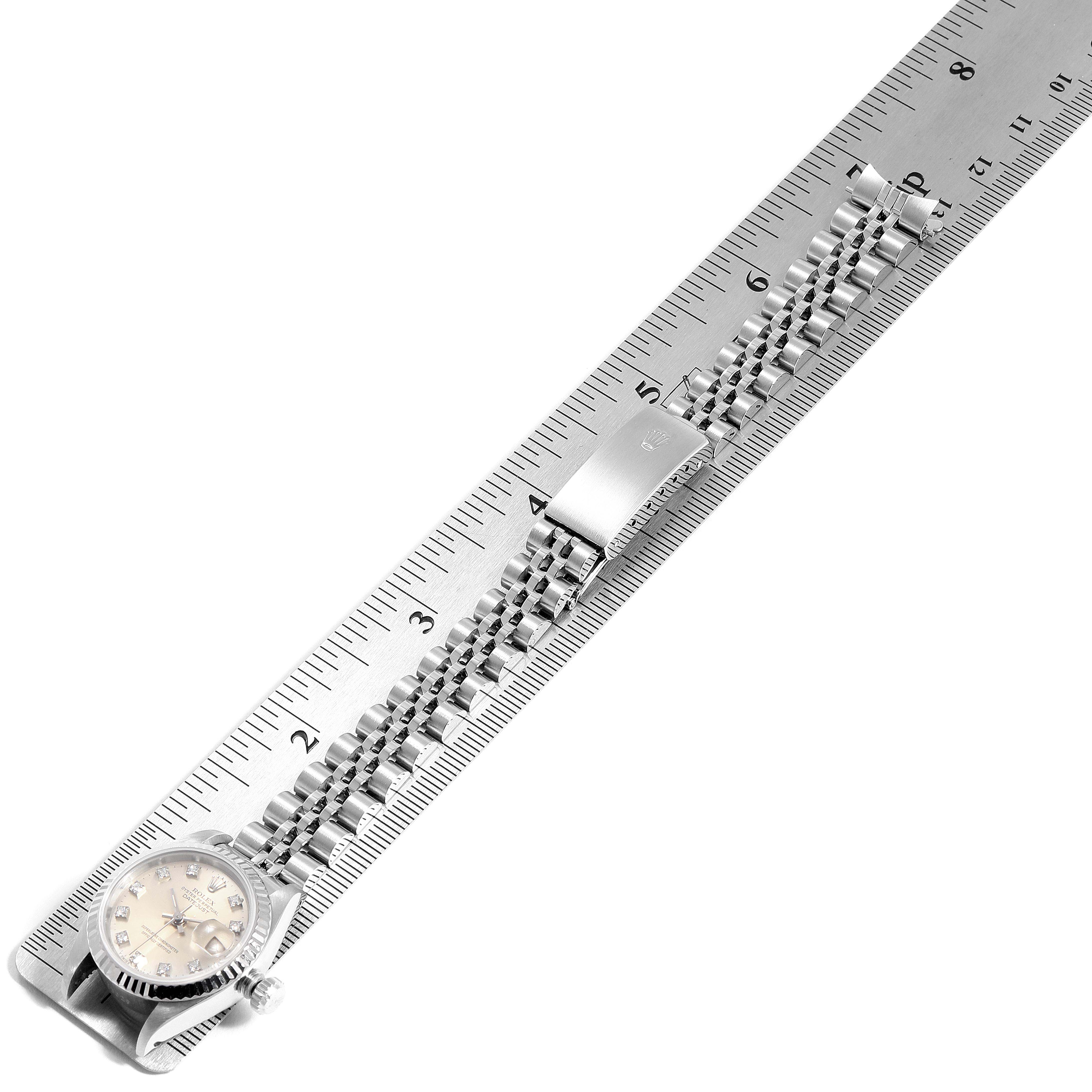 This image shows a Rolex Datejust 69174 Women's Stainless Steel Silver Dial 69174 Women's Stainless Steel Silver Dial watch laid flat against a ruler, showcasing its face, bracelet, and clasp.