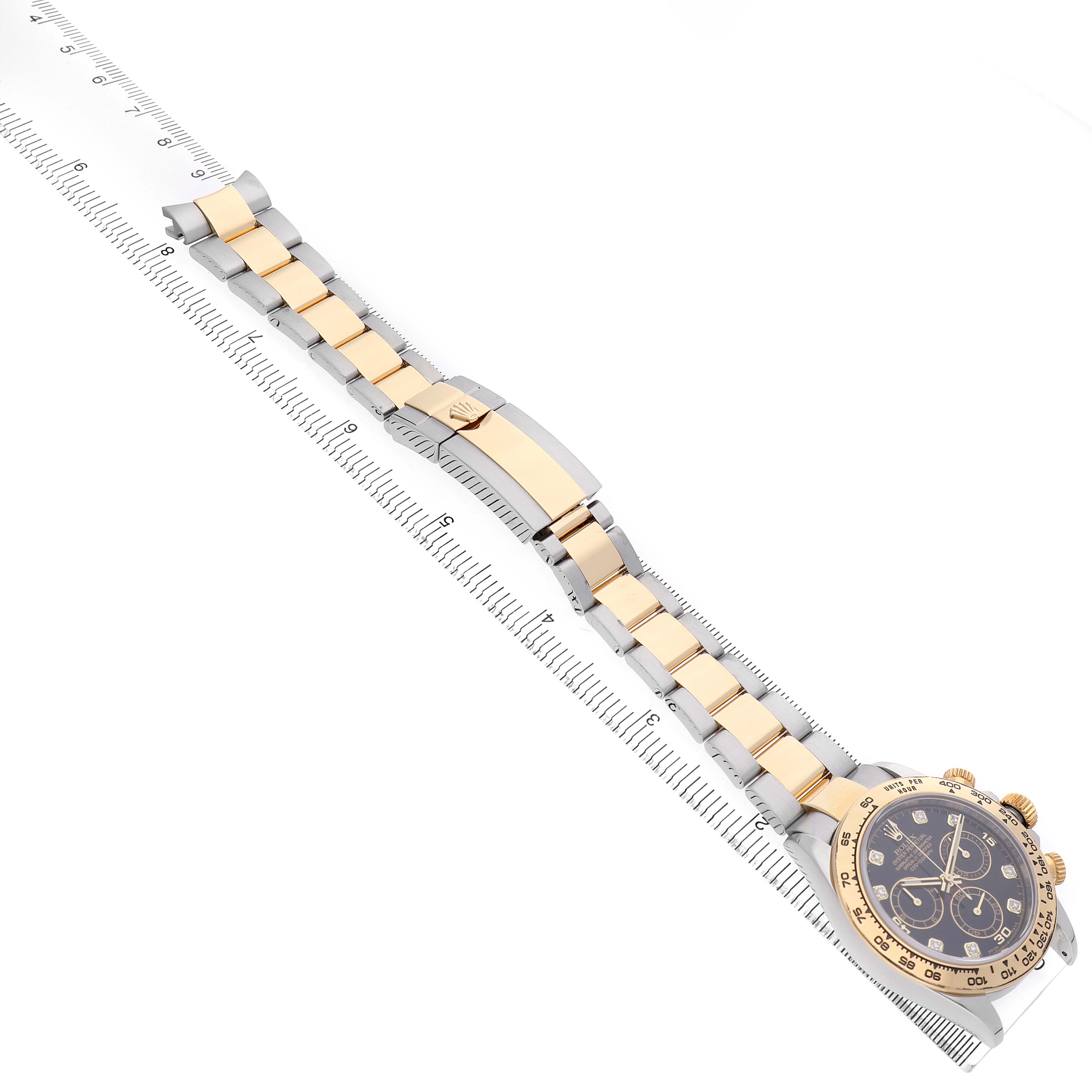 The Rolex Daytona 116503 Men's Steel and Gold (two tone) Black Dial watch is shown at an angle highlighting the face, bezel, and full bracelet, alongside a ruler for scale.