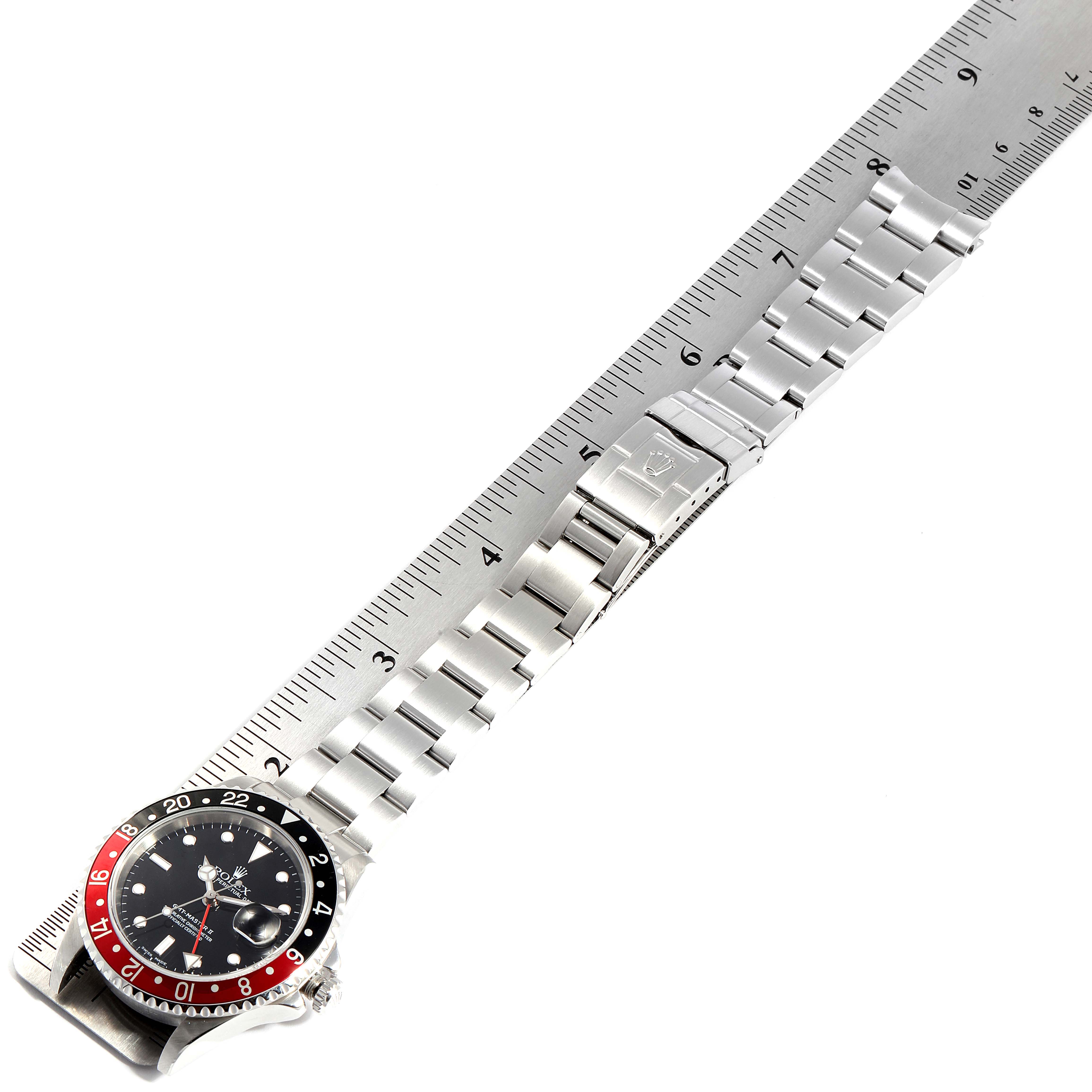 The image shows the Rolex GMT-Master 16710 Men
s Stainless Steel Black Dial 16710 Men
s Stainless Steel Black Dial watch laid flat, exhibiting its dial, bezel, and bracelet alongside a ruler.